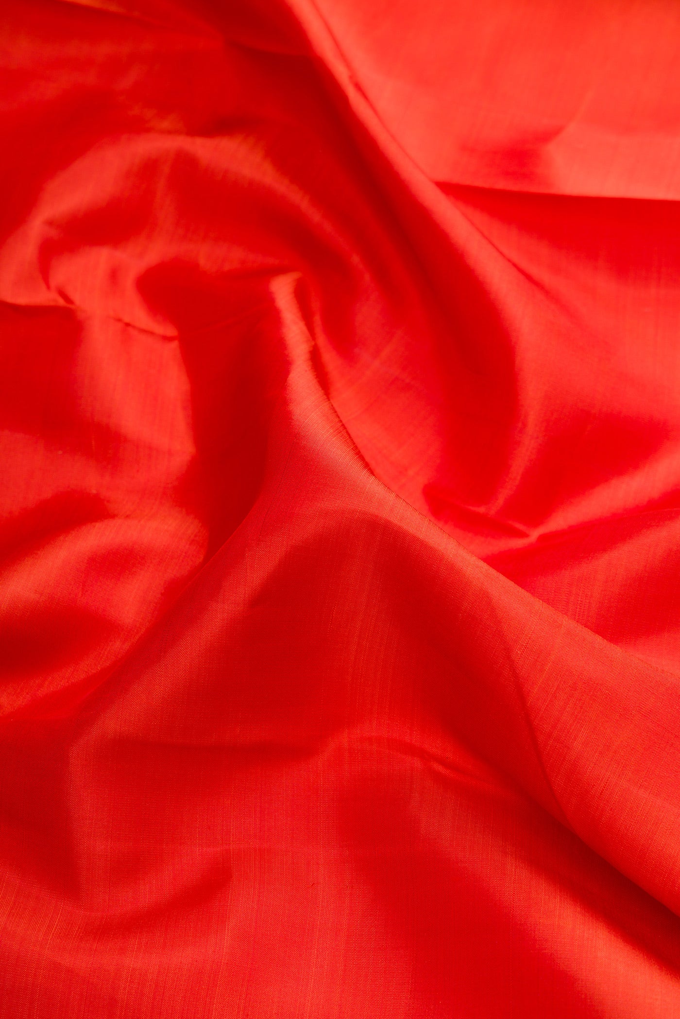 Close up of Brick Orange Dual Tone Kanjivaram Silk Saree with Plain Body and Zari Border.  displaying folds