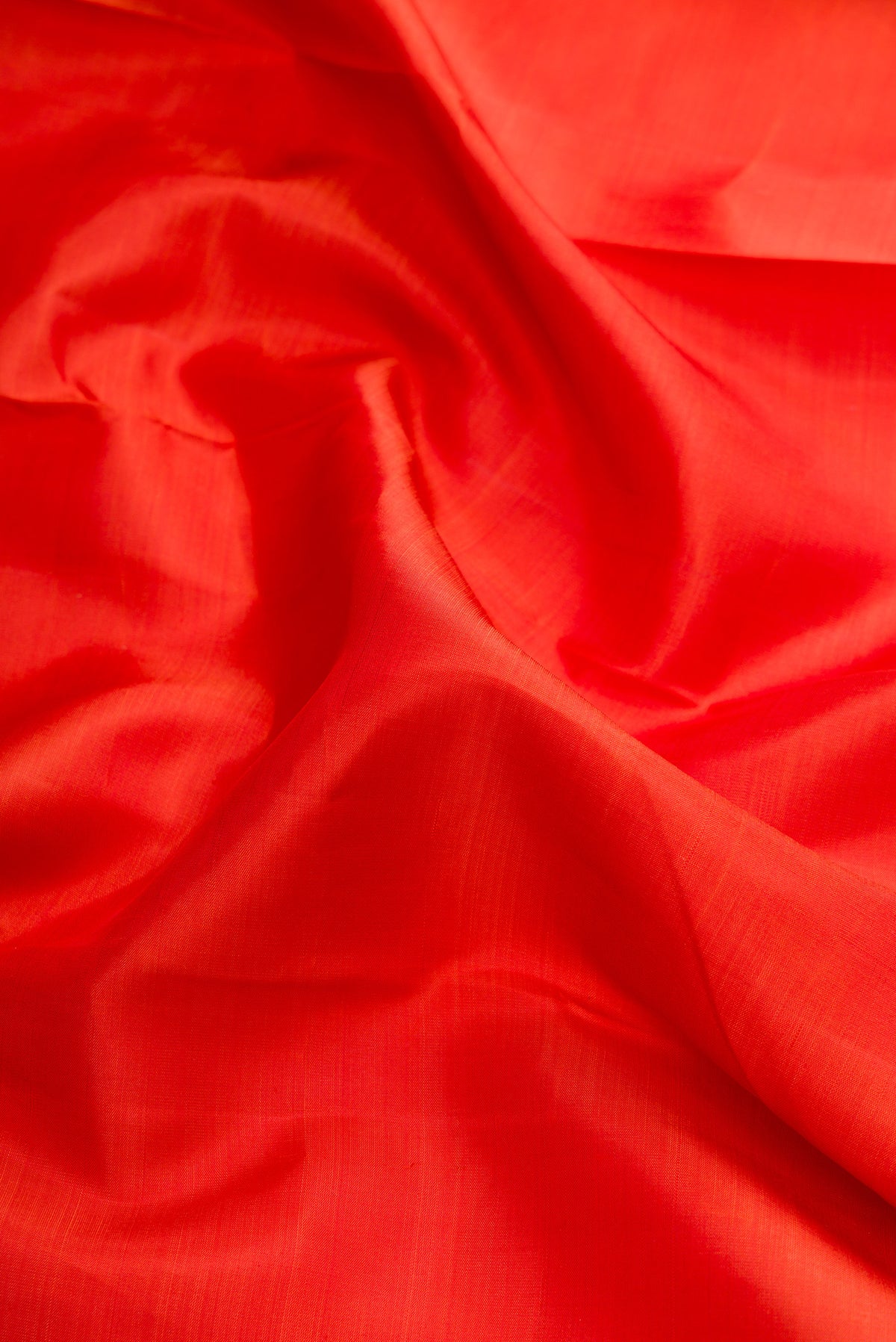 Close up of Brick Orange Dual Tone Kanjivaram Silk Saree with Plain Body and Zari Border.  displaying folds