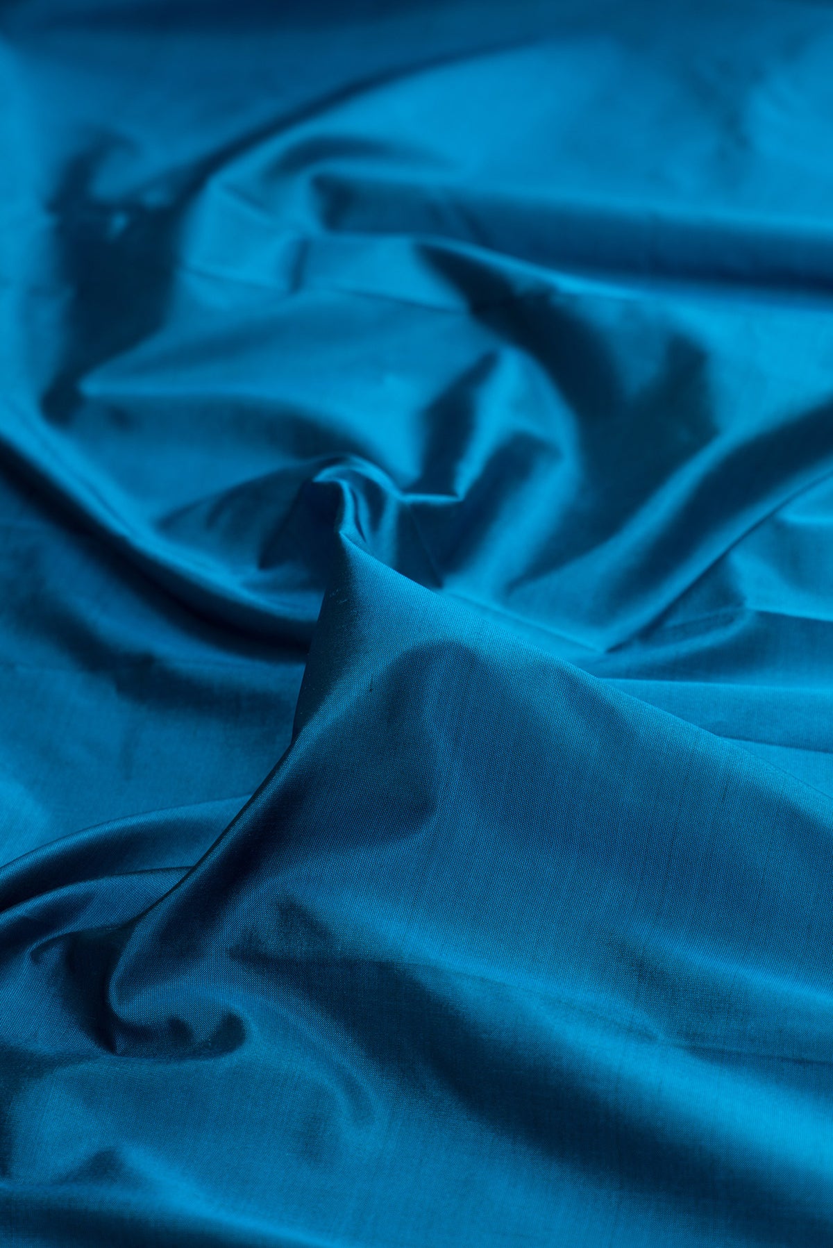 Close up of Pure Silk Peacock Blue Bangalore Saree with Plain Body and Temple Border.  displaying folds