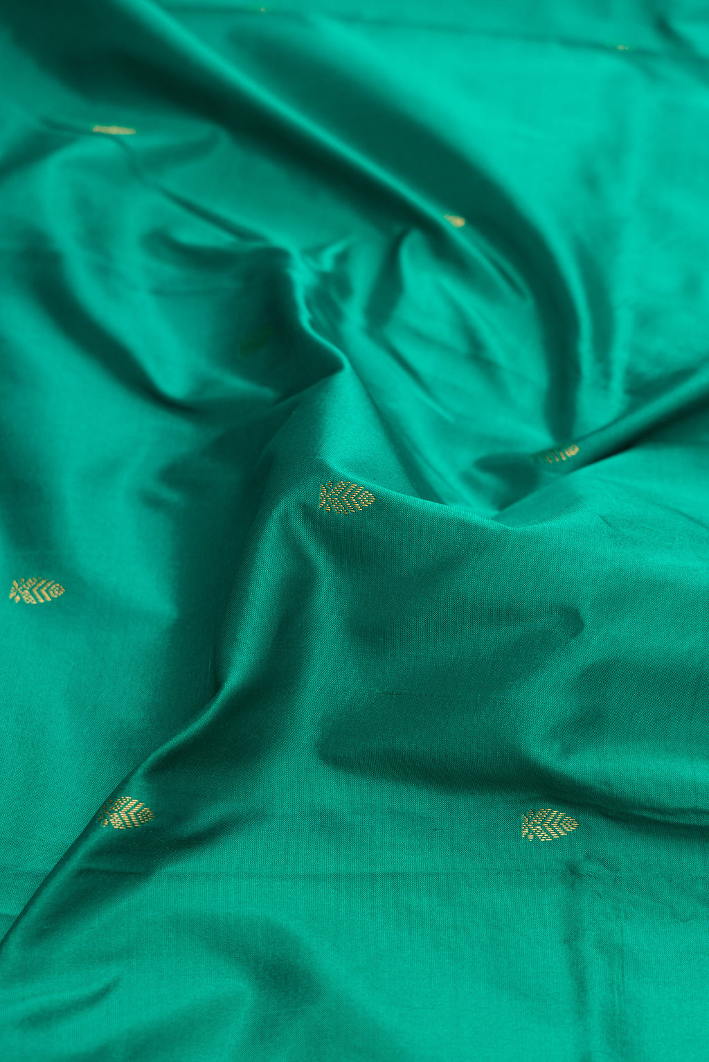 Close up of Green Dual Tone Kanchipuram Silk Saree with Zari Butta on the body and Zari Border.  displaying folds