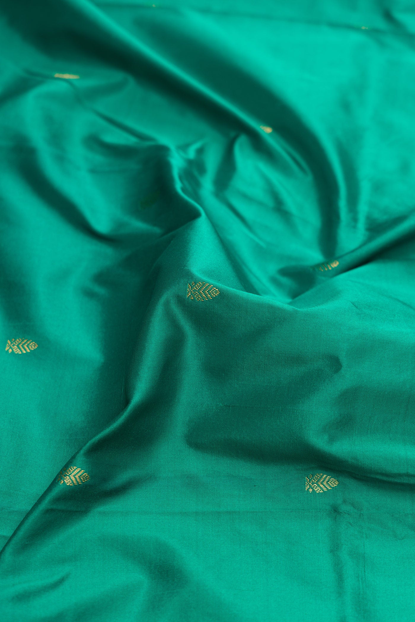 Close up of Green Dual Tone Kanchipuram Silk Saree with Zari Butta on the body and Zari Border.  displaying folds