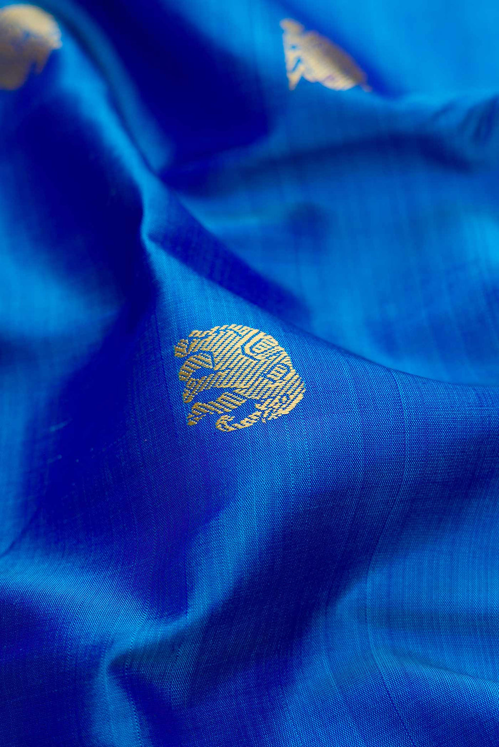 Close up of Royal Blue Dual Tone Kanjivaram Silk Saree with Thread Butta on the body and Zari And Thread Border.  displaying folds