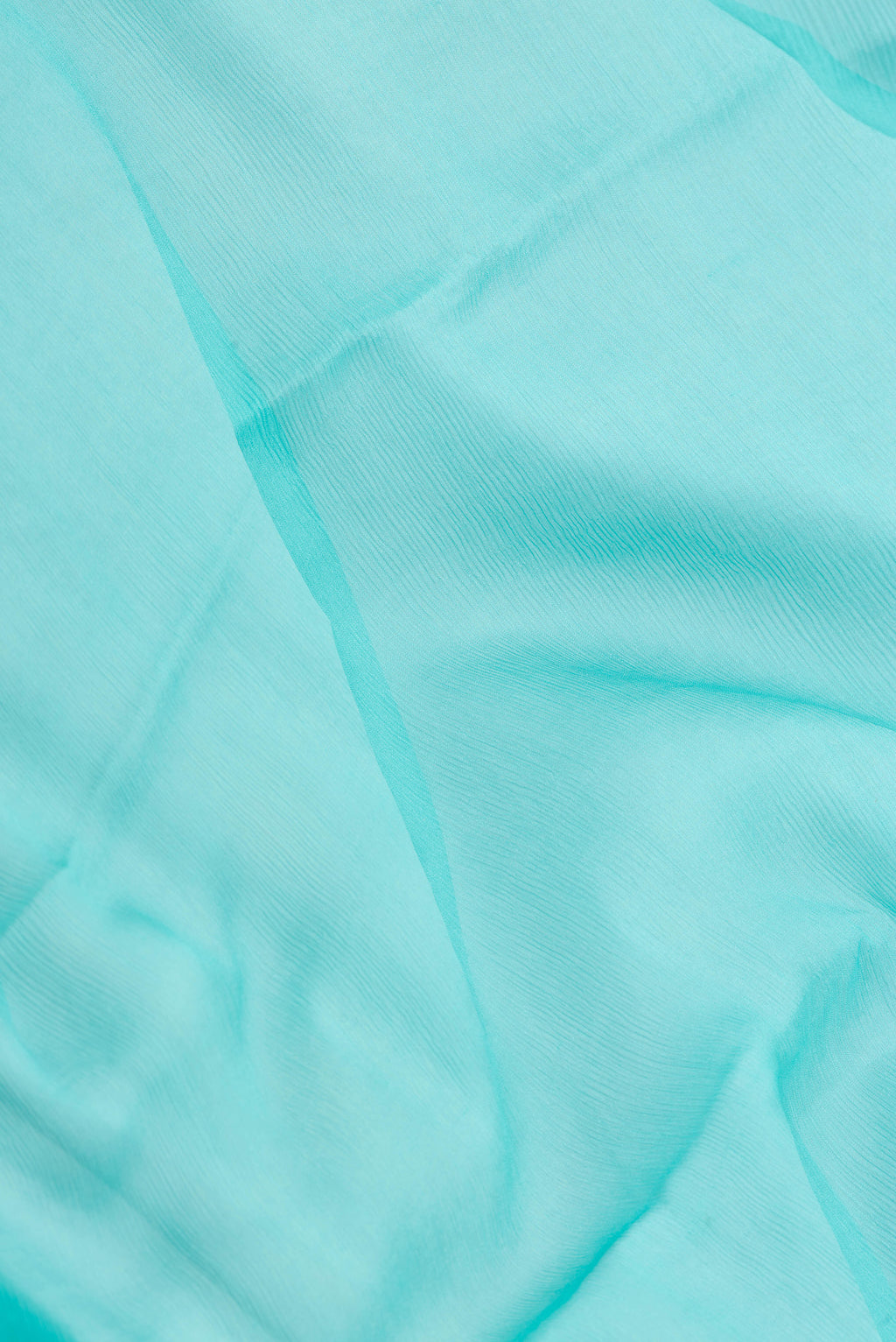 Close up of Sky Blue Mysore Chiffon Saree with Plain Body and Zari Border.  displaying folds