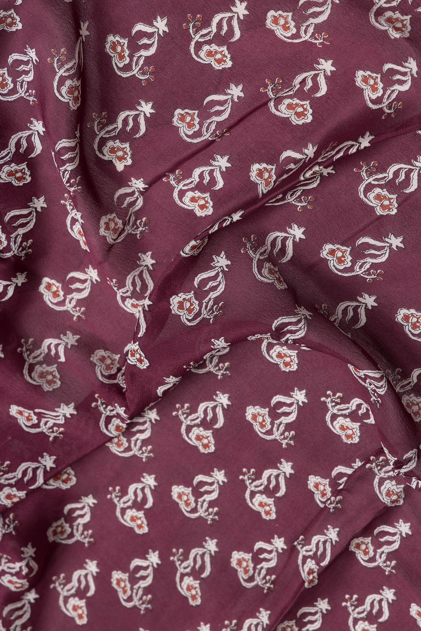 Close up of Maroon Dual Tone Mysore Crepe Saree with Printed design on the body and Zari Border.  displaying folds
