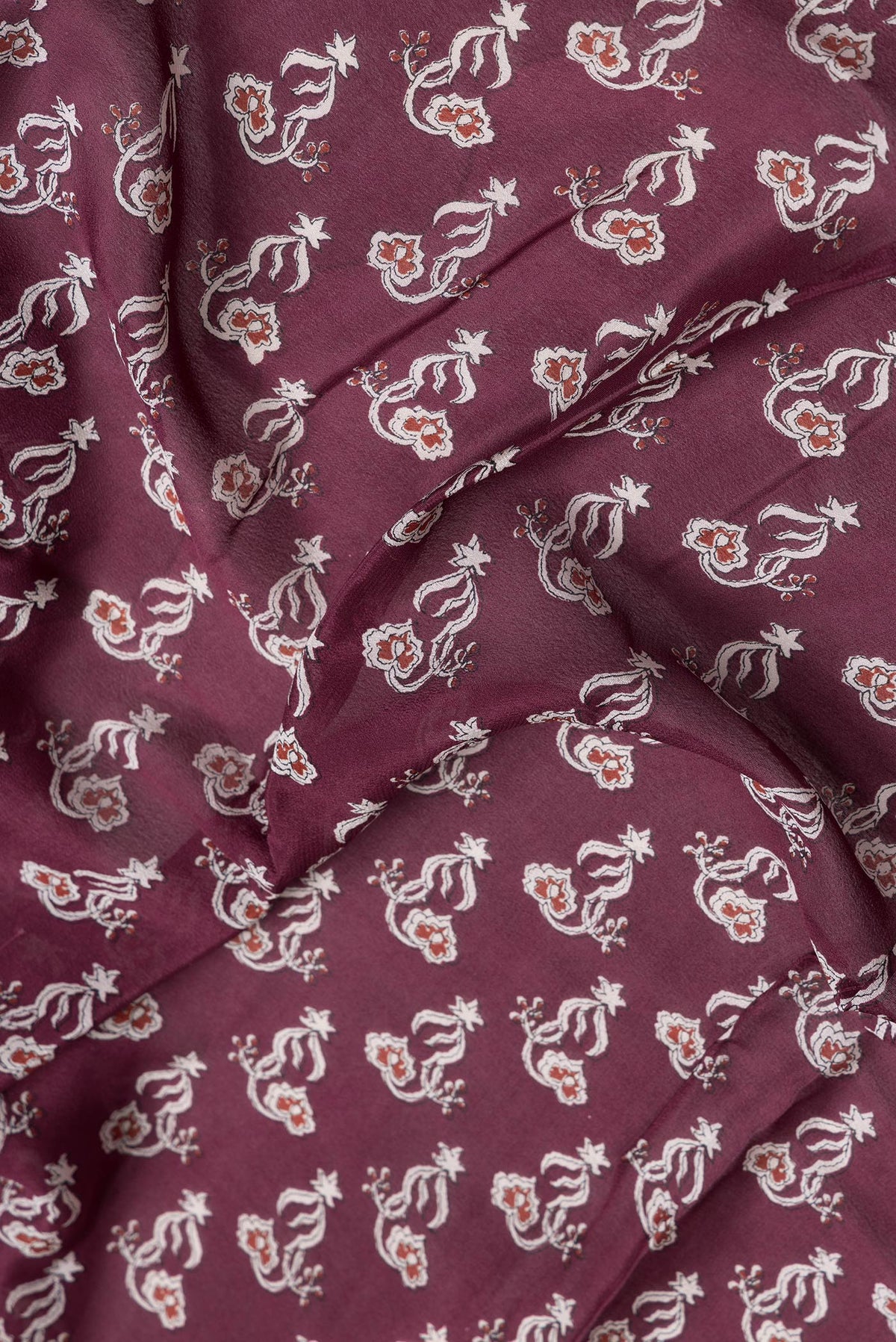 Close up of Maroon Dual Tone Mysore Crepe Saree with Printed design on the body and Zari Border.  displaying folds