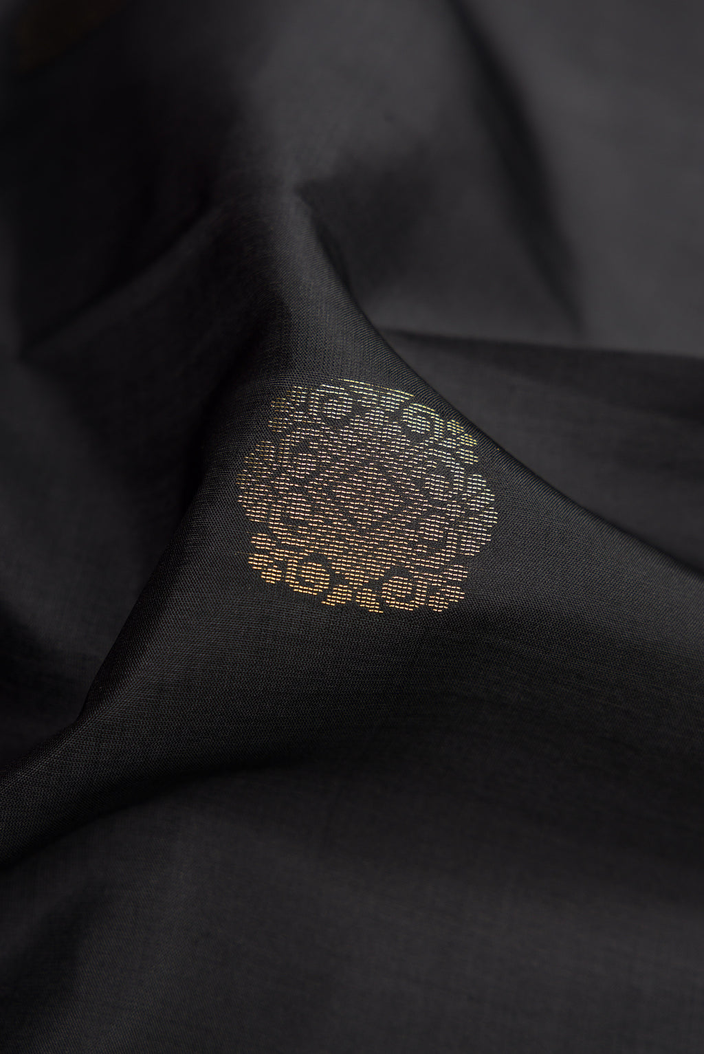 Close up of Black Dual Tone Kanjivaram Silk Saree with Zari Butta on the body and Zari Border.  displaying folds
