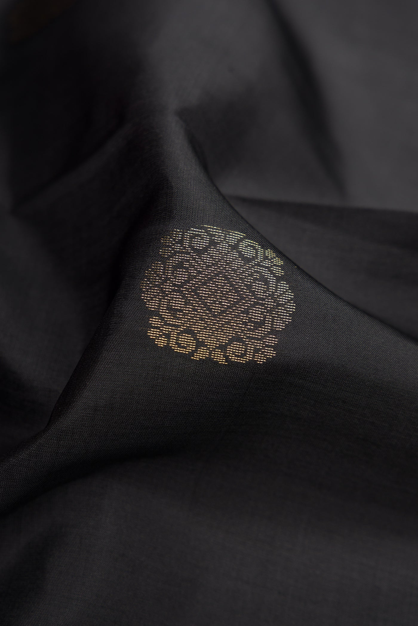 Close up of Black Dual Tone Kanjivaram Silk Saree with Zari Butta on the body and Zari Border.  displaying folds