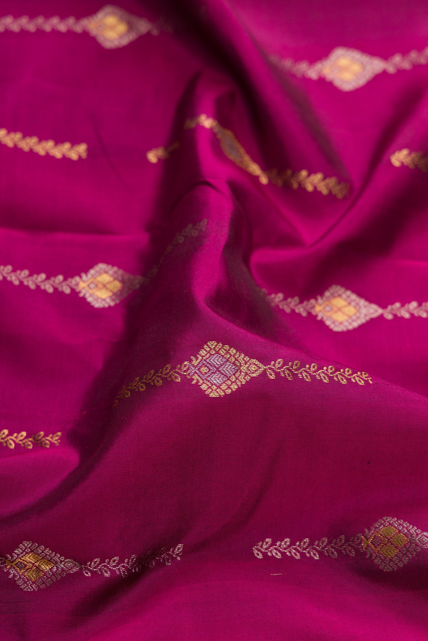 Close up of Magenta Dual Tone Kanchipuram Silk Saree with Zari Butta on the body and Zari Border.  displaying folds
