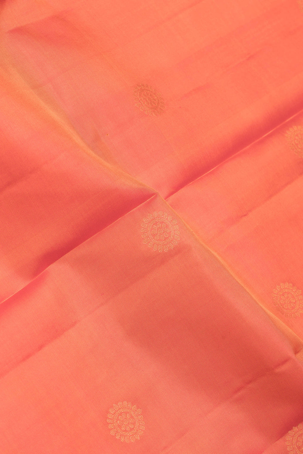 Close up of Orange Dual Tone Kanchipuram Silk Saree with Zari Butta on the body and Zari Border.  displaying folds