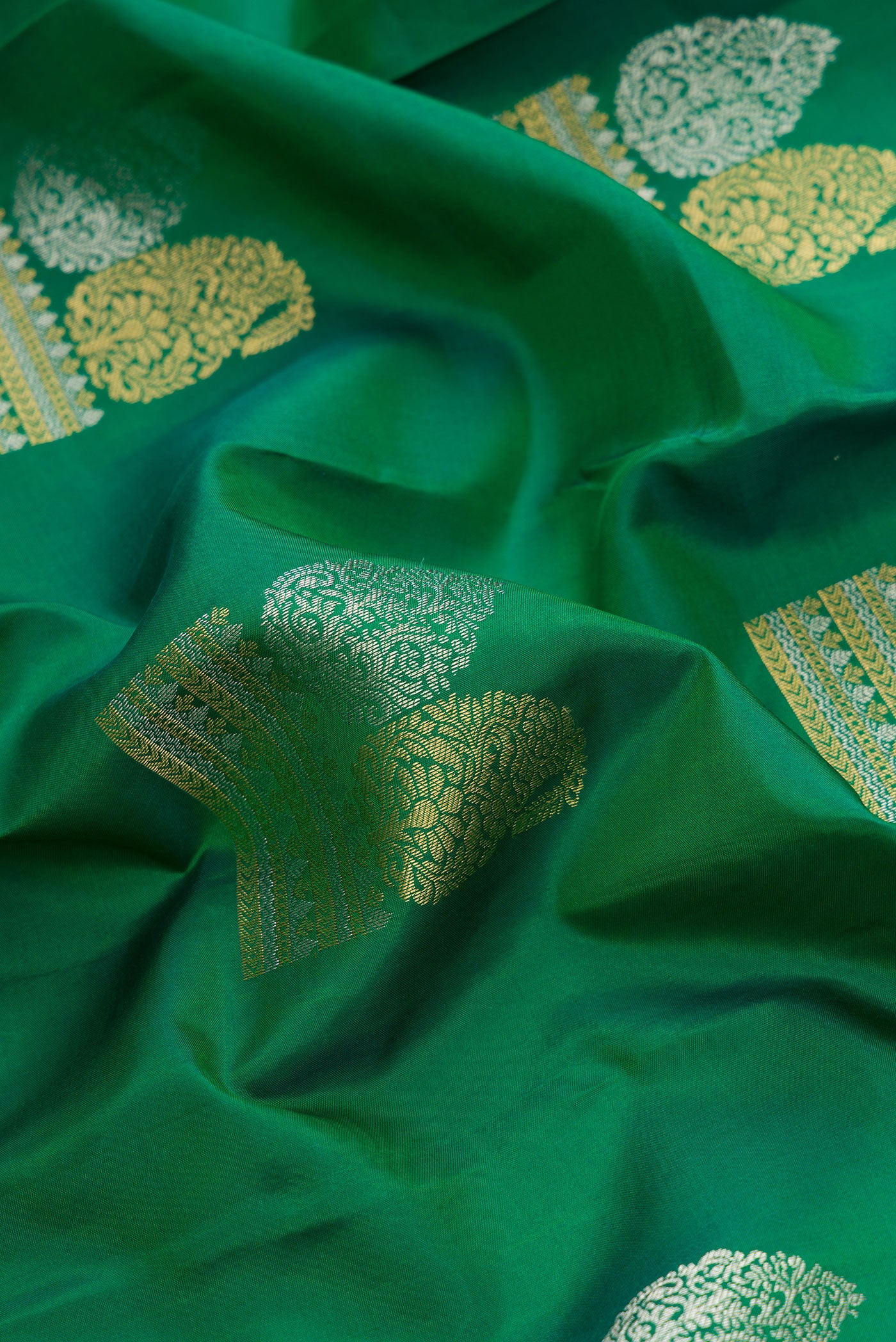 Close up of Green Dual Tone Kanchipuram Silk Saree with Zari Butta on the body and Zari Border.  displaying folds