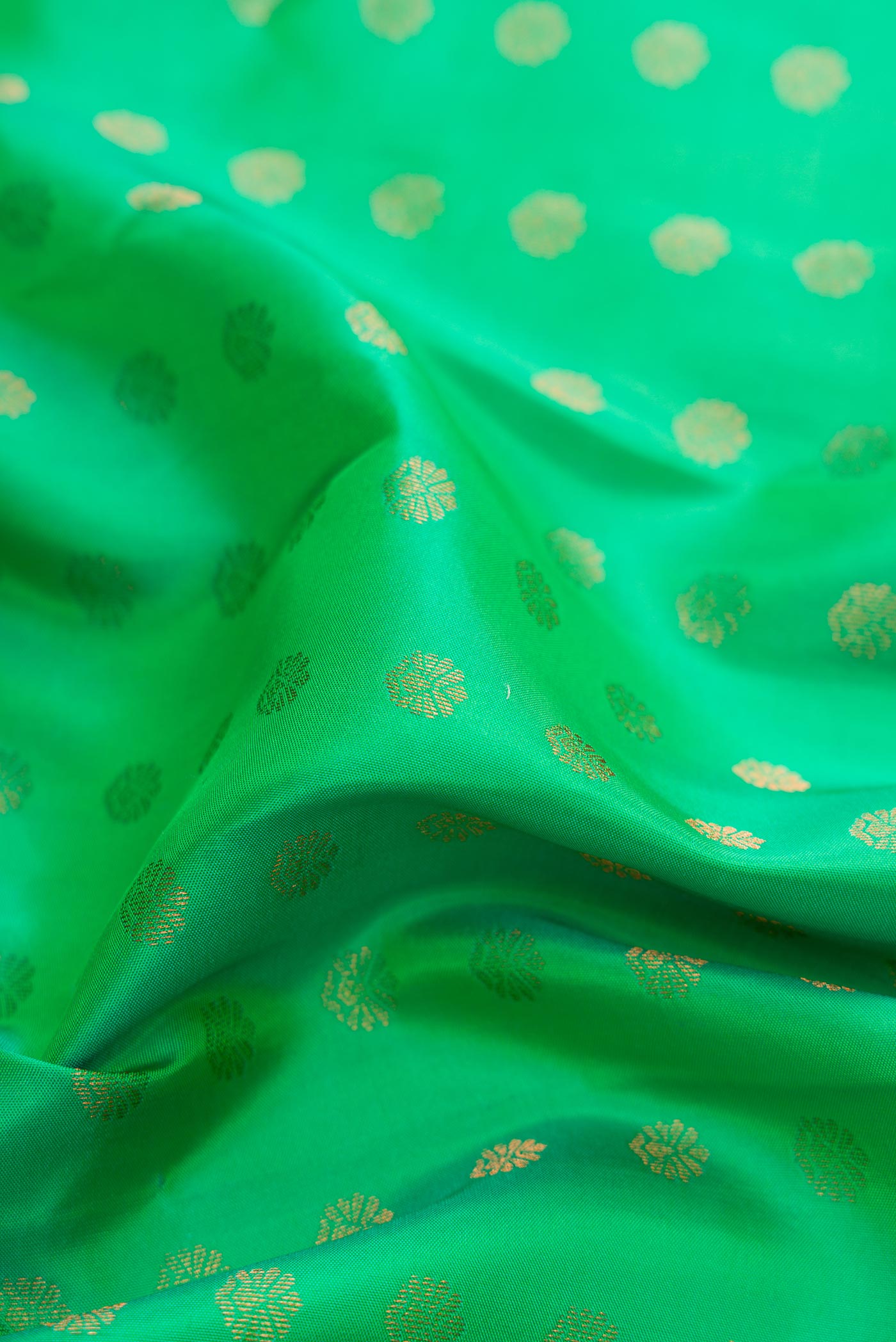 Close up of Green Dual Tone Kanchipuram Silk Saree with Zari Butta on the body and Zari Border displaying folds