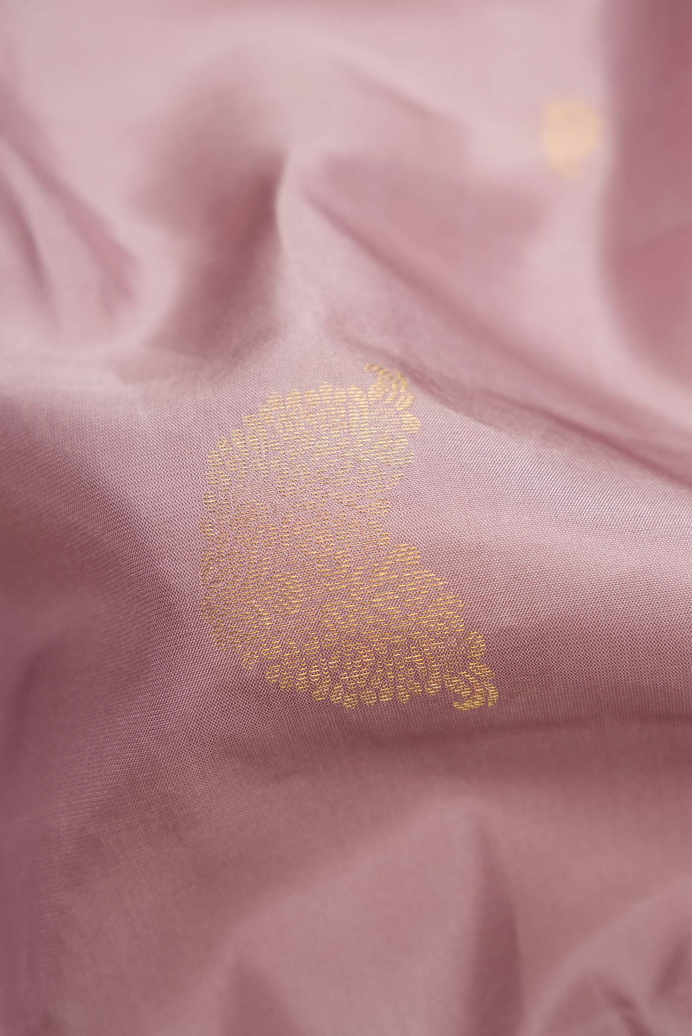 Close up of Rose Gold Dual Tone Kanchipuram Silk Saree with Zari Butta on the body and Zari Border.  displaying folds