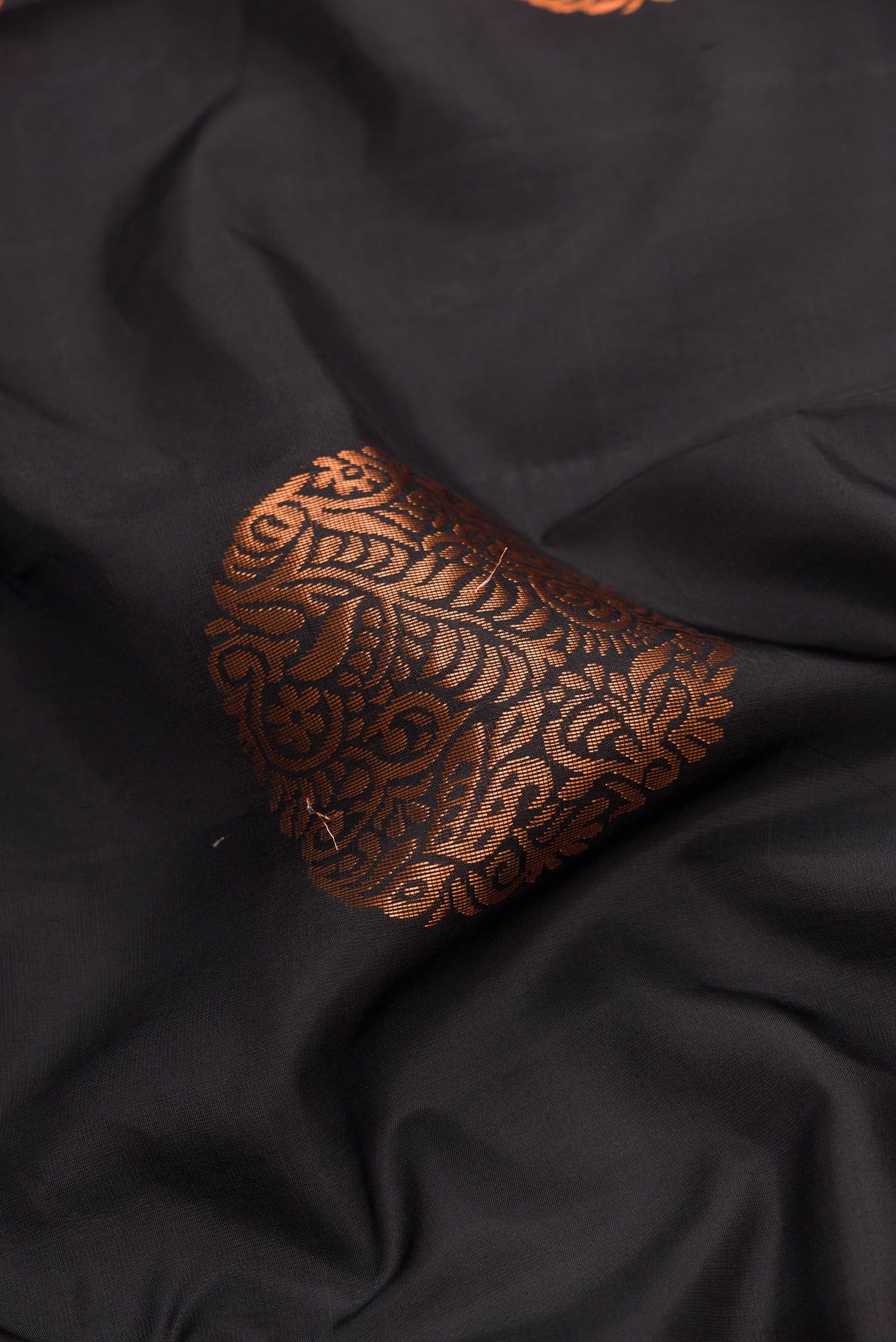 Close up of Black Dual Tone Kanjivaram Silk Saree with Zari Butta on the body and Without Border.  displaying folds