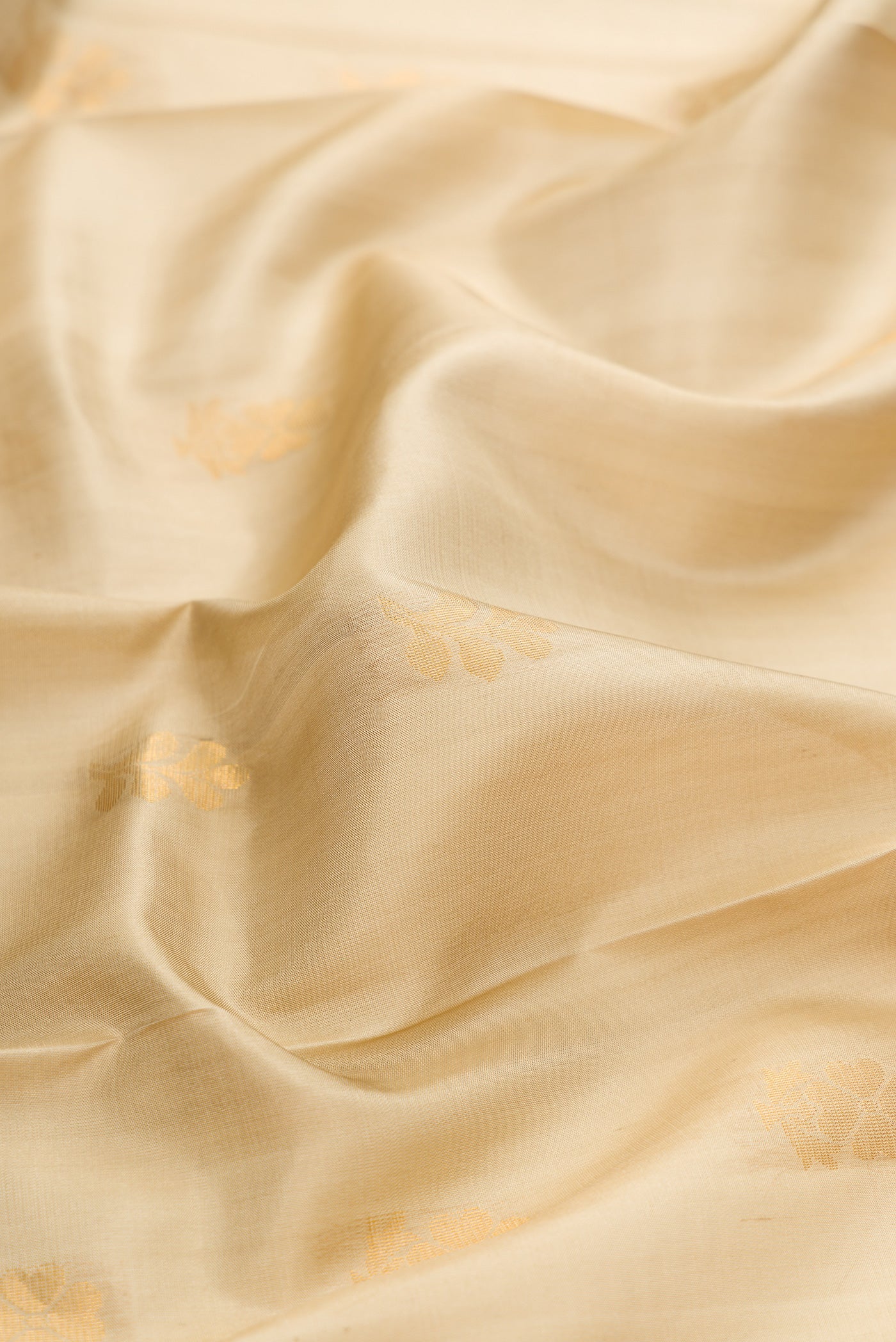 Close up of Beige Dual Tone Soft Silk Saree with Zari Butta on the body and Zari Border.  displaying folds