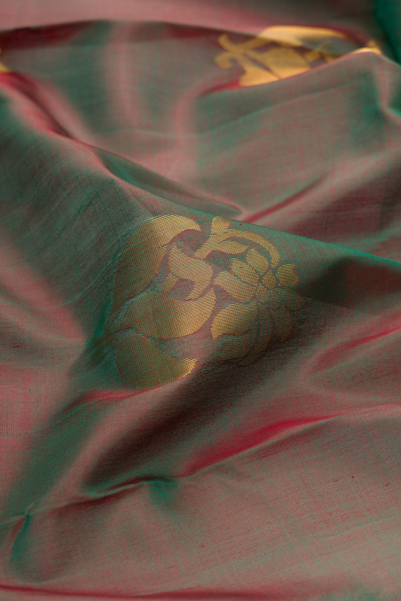 Close up of Green Dual Tone Soft Silk Saree with Zari Butta on the body and Zari Border.  displaying folds