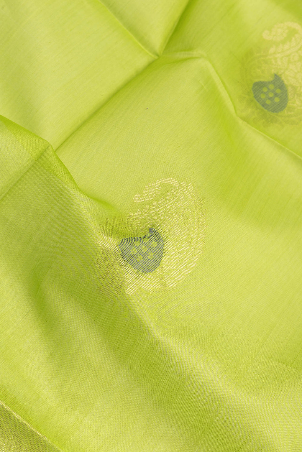Close up of Parrot Green Silk Cotton Saree with Zari Butta on the body and Zari Border.  displaying folds