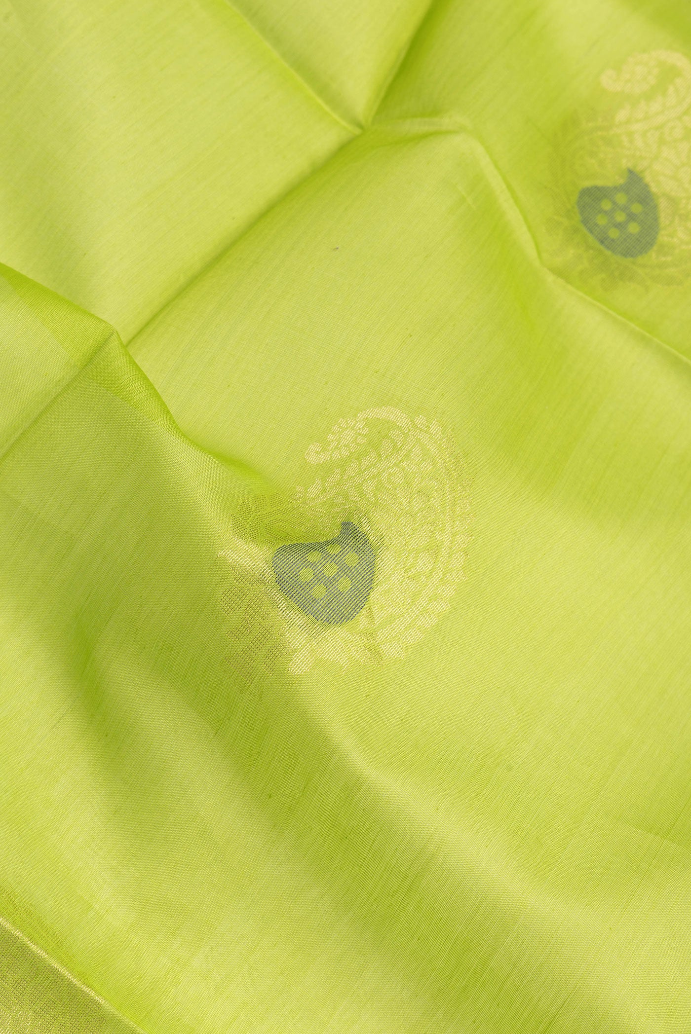 Close up of Parrot Green Silk Cotton Saree with Zari Butta on the body and Zari Border.  displaying folds
