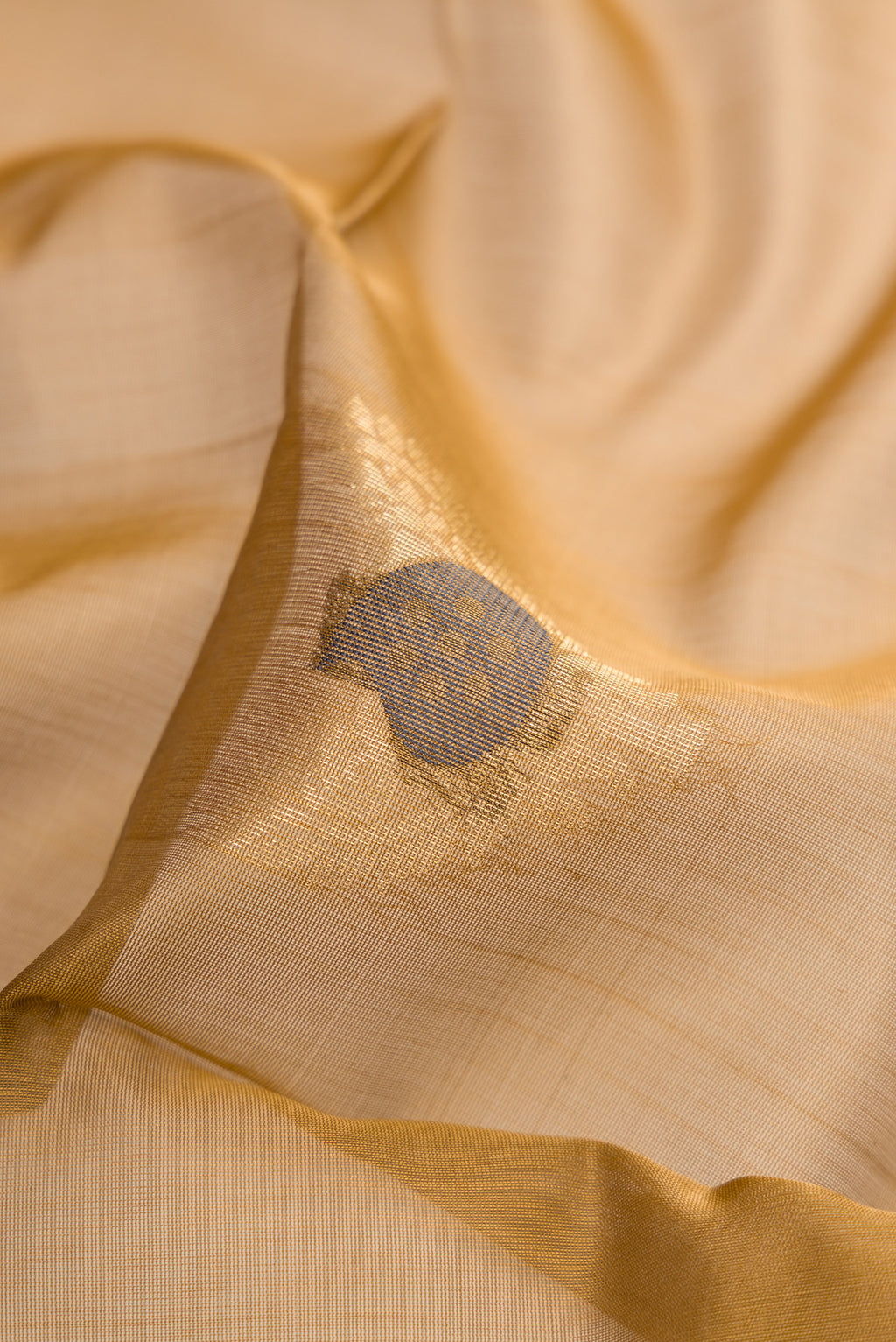 Close up of Brown Silk Cotton Saree with Zari And Thread Butta on the body and Zari Border.  displaying folds