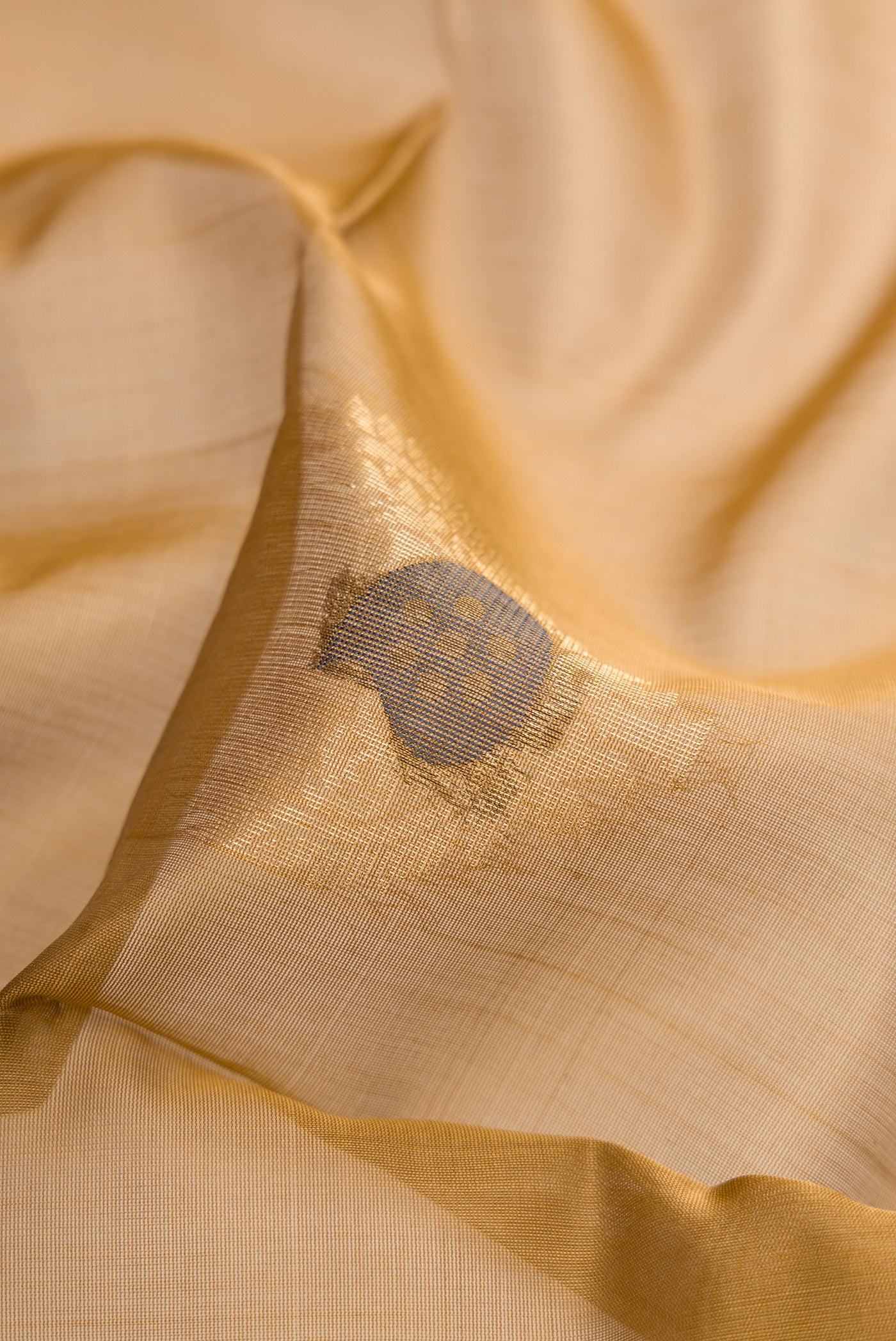Close up of Brown Silk Cotton Saree with Zari And Thread Butta on the body and Zari Border.  displaying folds