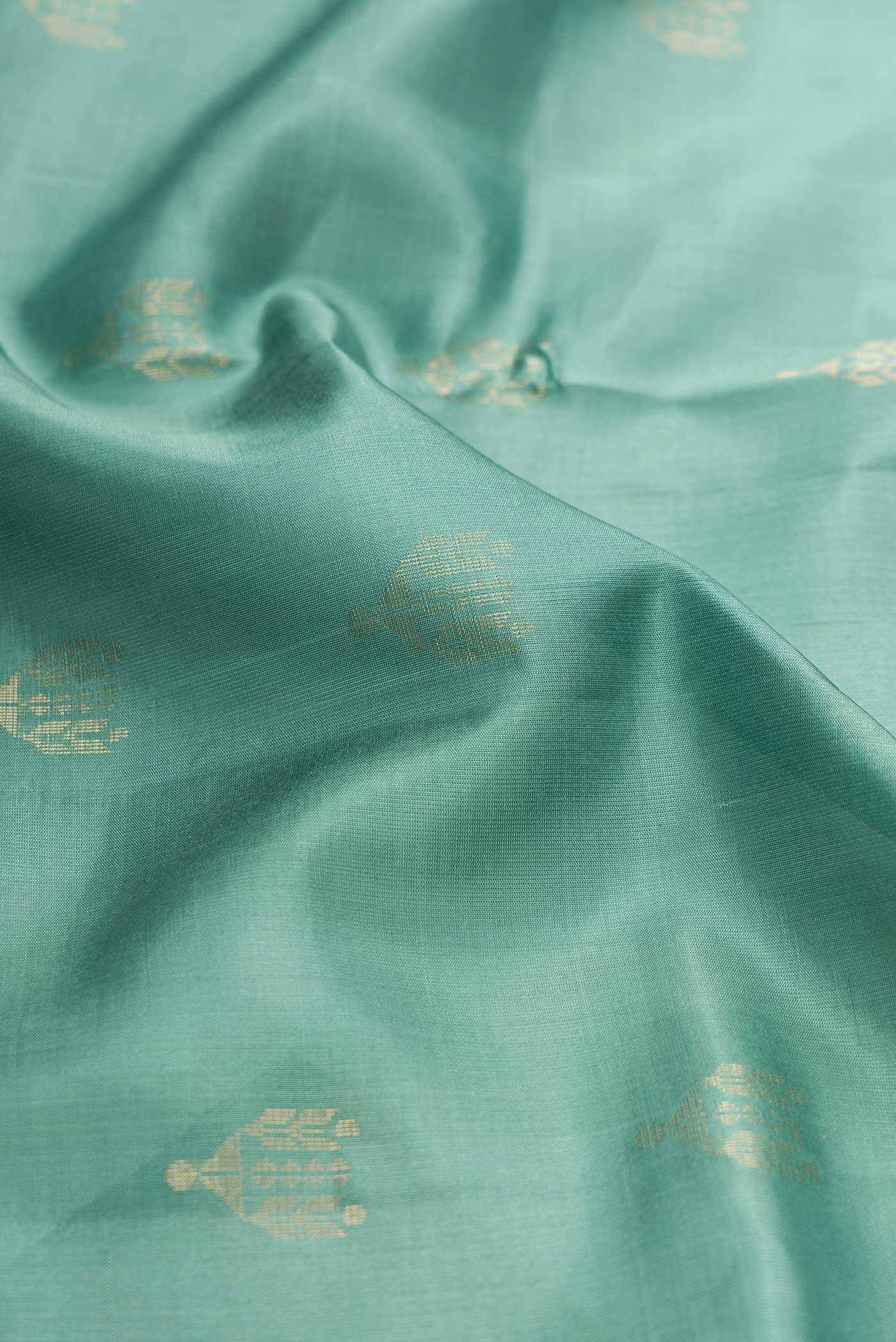 Close up of Green Dual Tone Soft Silk Saree with Zari Butta on the body and Zari Border displaying folds