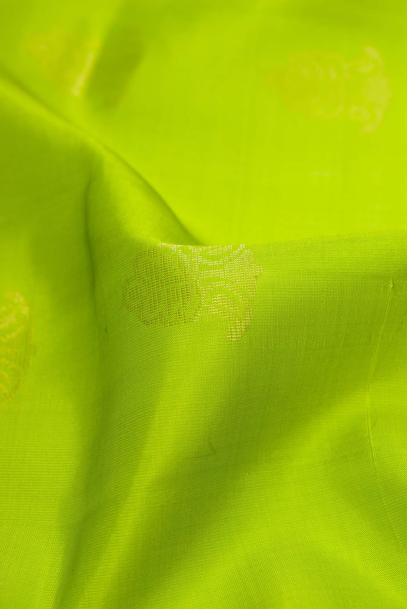 Close up of Parrot Green Dual Tone Soft Silk Saree with Zari Butta on the body and Zari Border displaying folds