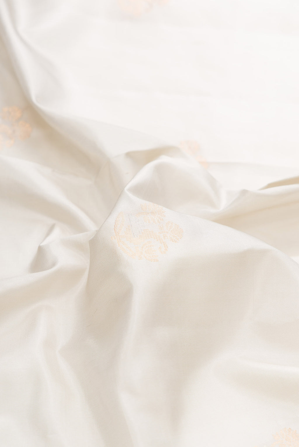 Close up of Off White Dual Tone Soft Silk Saree with Zari Butta on the body and Zari Border displaying folds