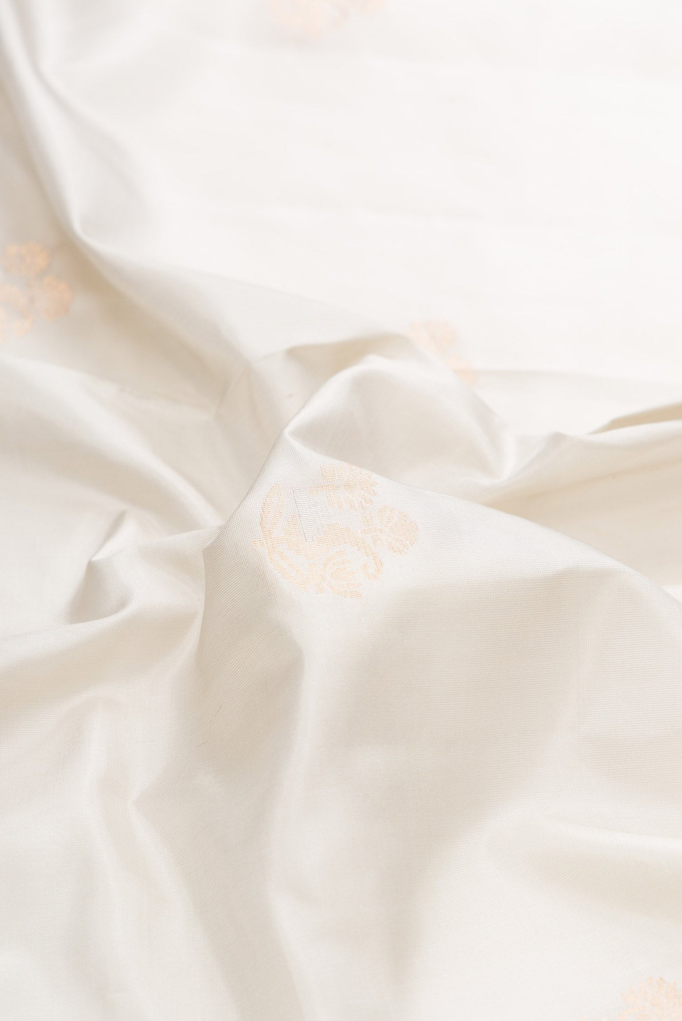 Close up of Off White Dual Tone Soft Silk Saree with Zari Butta on the body and Zari Border displaying folds