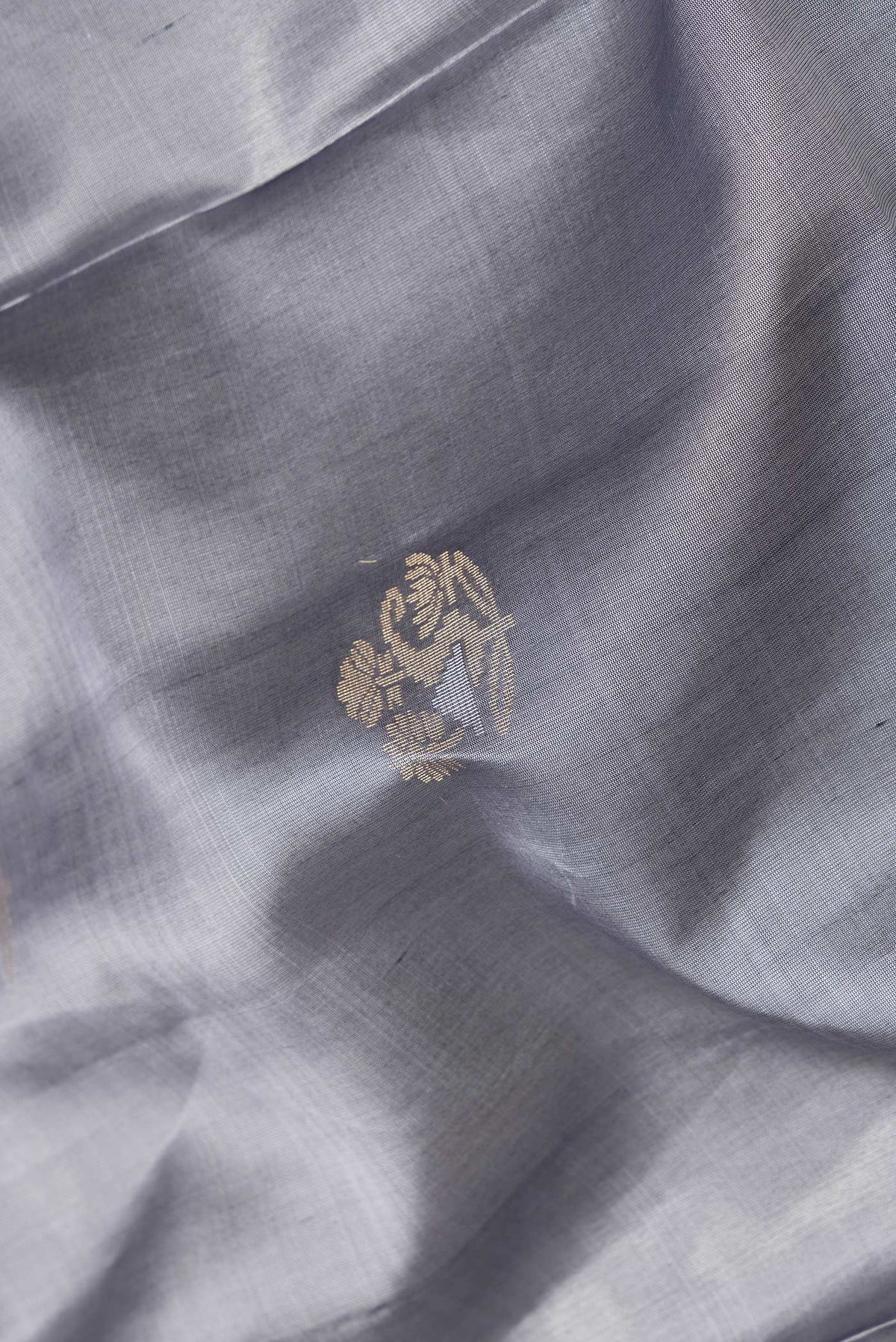 Close up of Grey Dual Tone Soft Silk Saree with Zari Butta on the body and Zari Border.  displaying folds