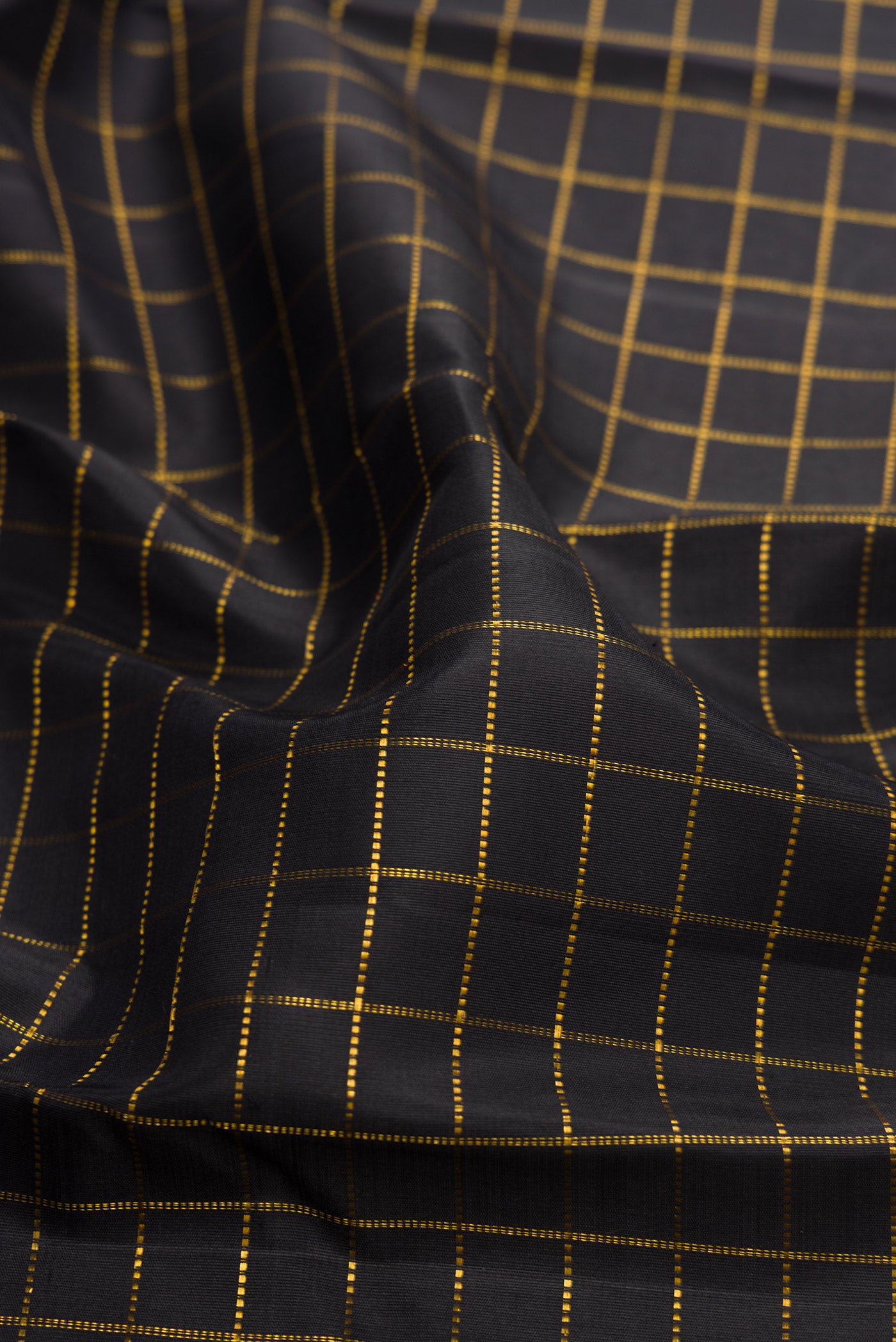 Close up of Black Dual Tone Kanchipuram Silk Saree with Checked design on the body and Ganga Jamuna Border.  displaying folds