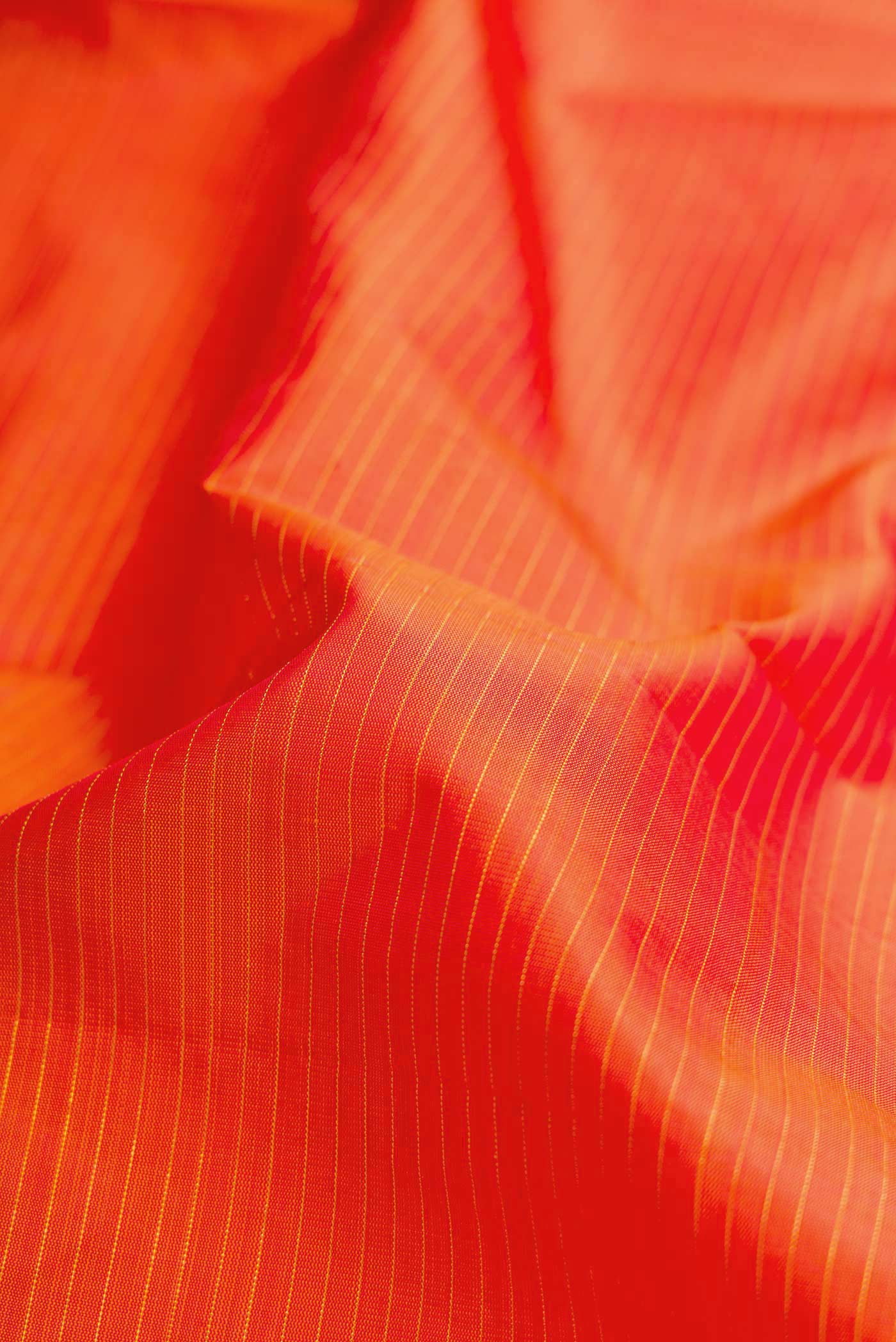 Close up of Orange Dual Tone Kanjivaram Silk Saree with Zari And Thread Butta on the body and Zari Border.  displaying folds