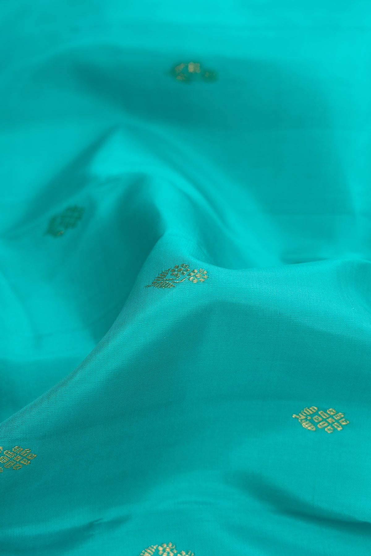 Close up of Sea Green Dual Tone Kanchipuram Silk Saree with Zari Butta on the body and Zari Border.  displaying folds