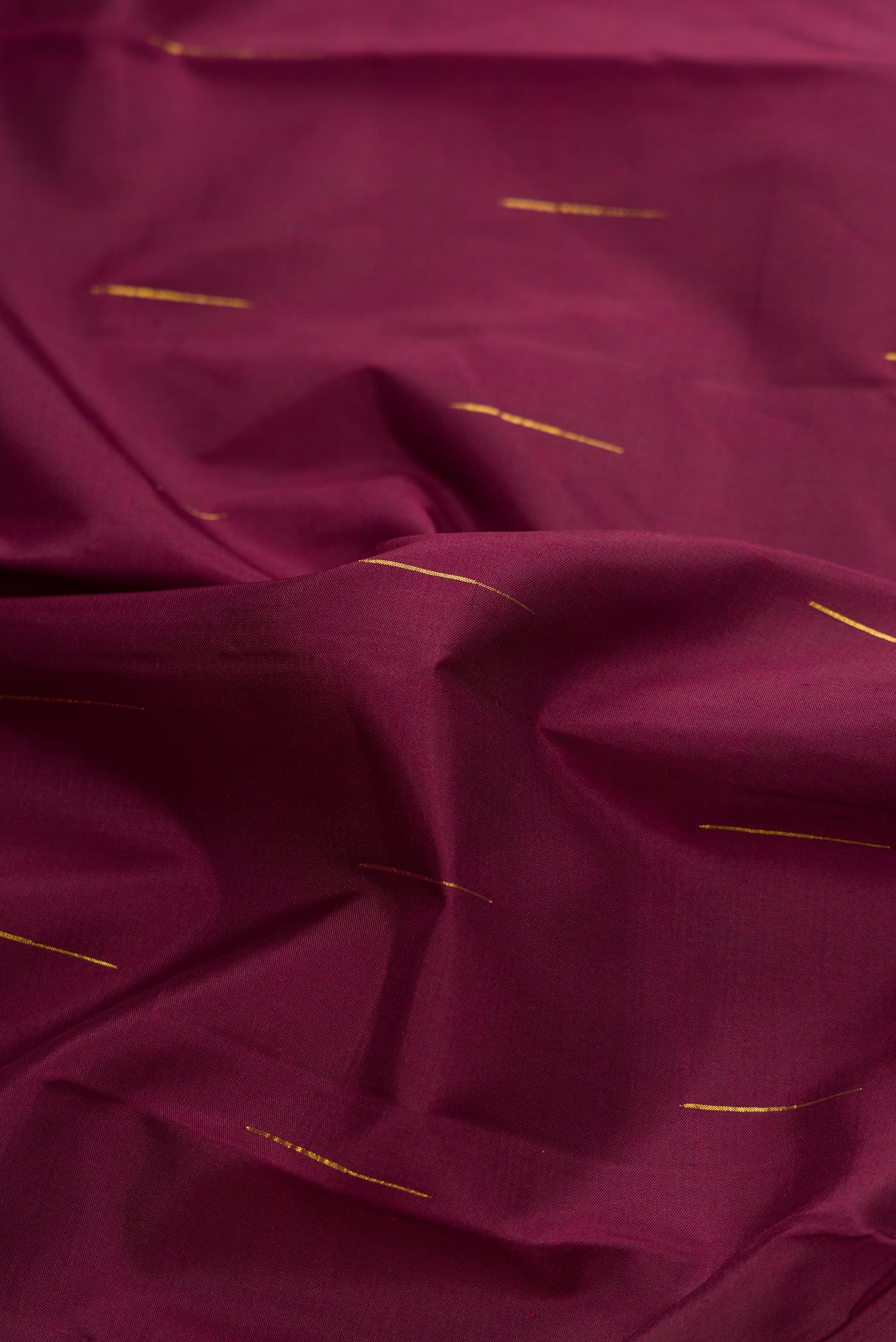 Close up of Burgundy Dual Tone Kanjivaram Silk Saree with Zari Butta on the body and Zari Border.  displaying folds