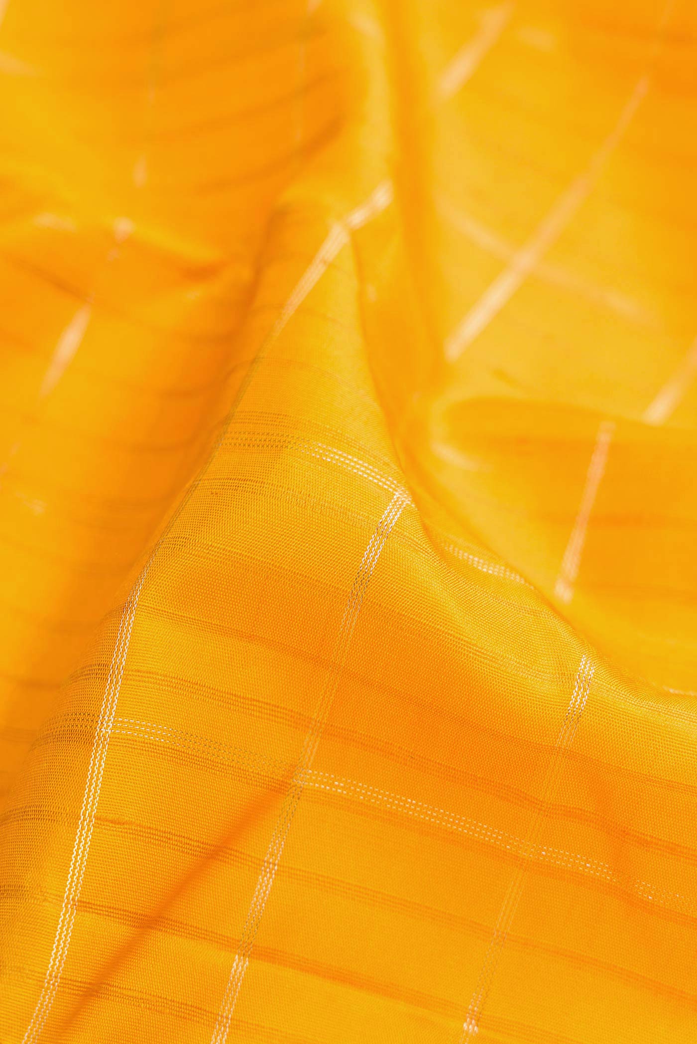 Close up of Mustard Dual Tone Kanchipuram Silk Saree with Checked design on the body and Zari Border.  displaying folds