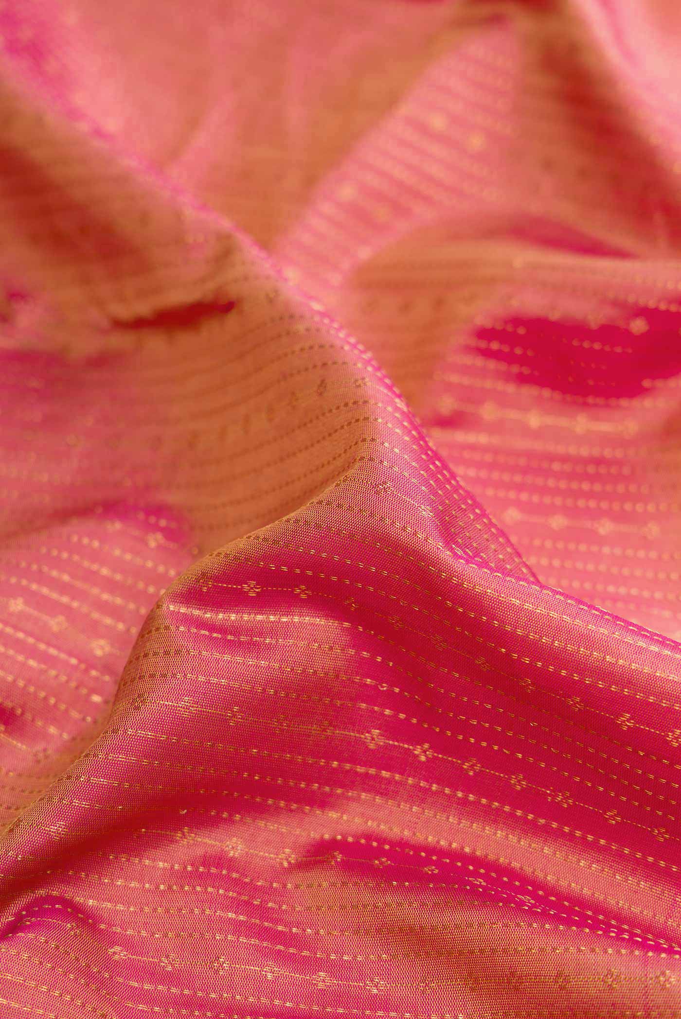 Close up of Golden Peach Dual Tone Kanchipuram Silk Saree with Stripes on the body and Zari Border.  displaying folds