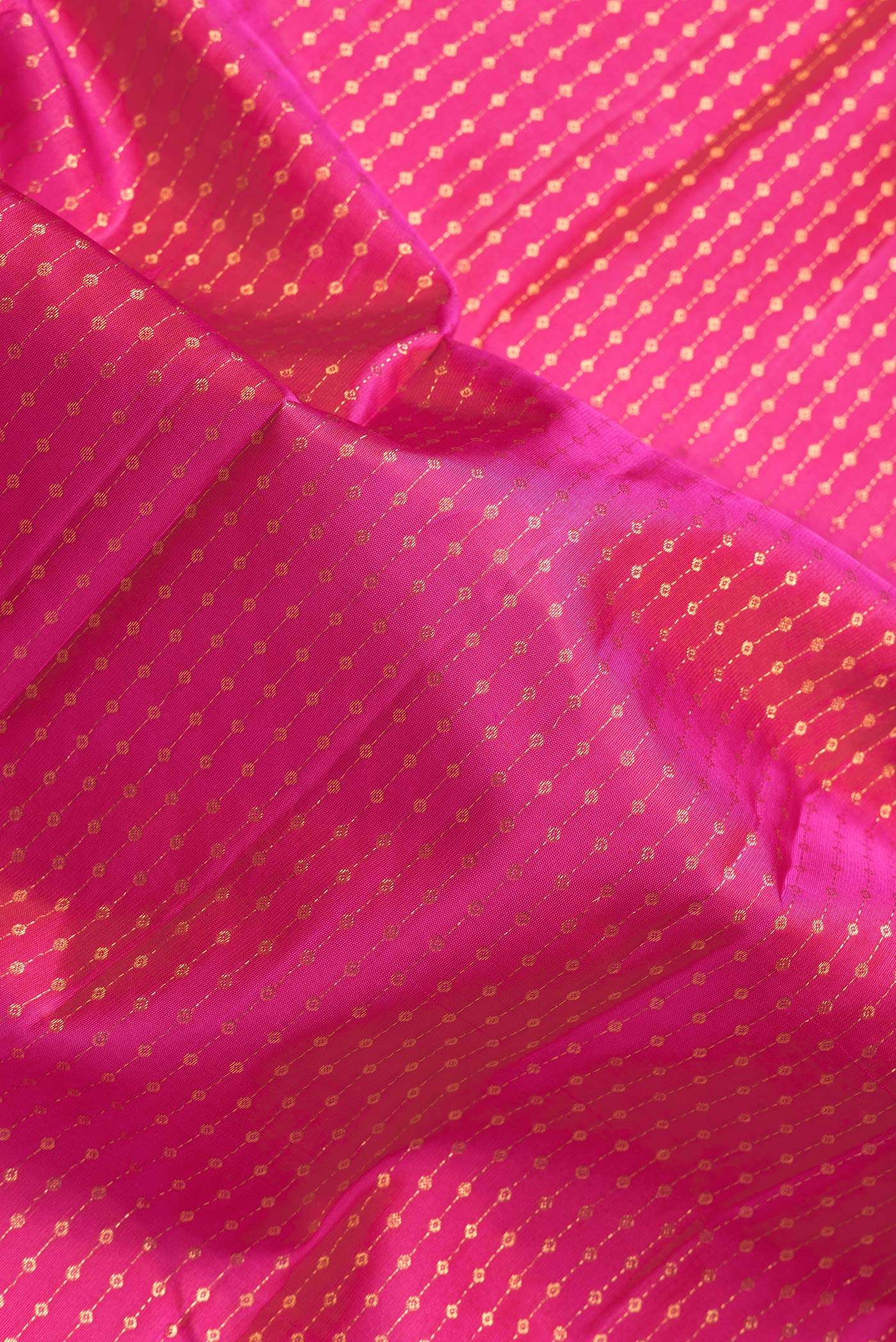Close up of Dark Pink Dual Tone Kanchipuram Silk Saree with Zari Butta on the body and Thin Zari Line.  displaying folds