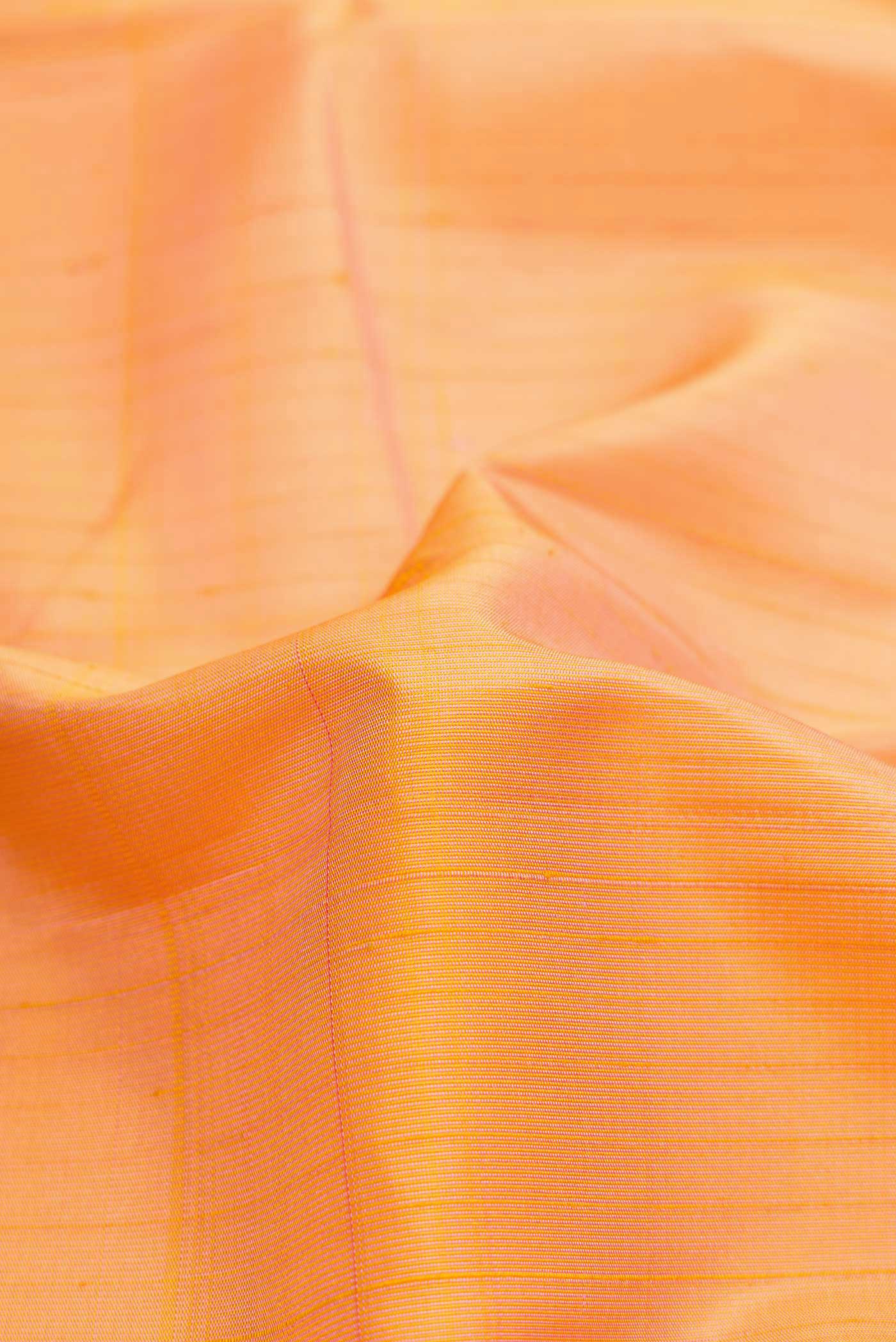 Close up of Golden Peach Dual Tone Kanchipuram Silk Saree with Stripes on the body and Zari Border.  displaying folds