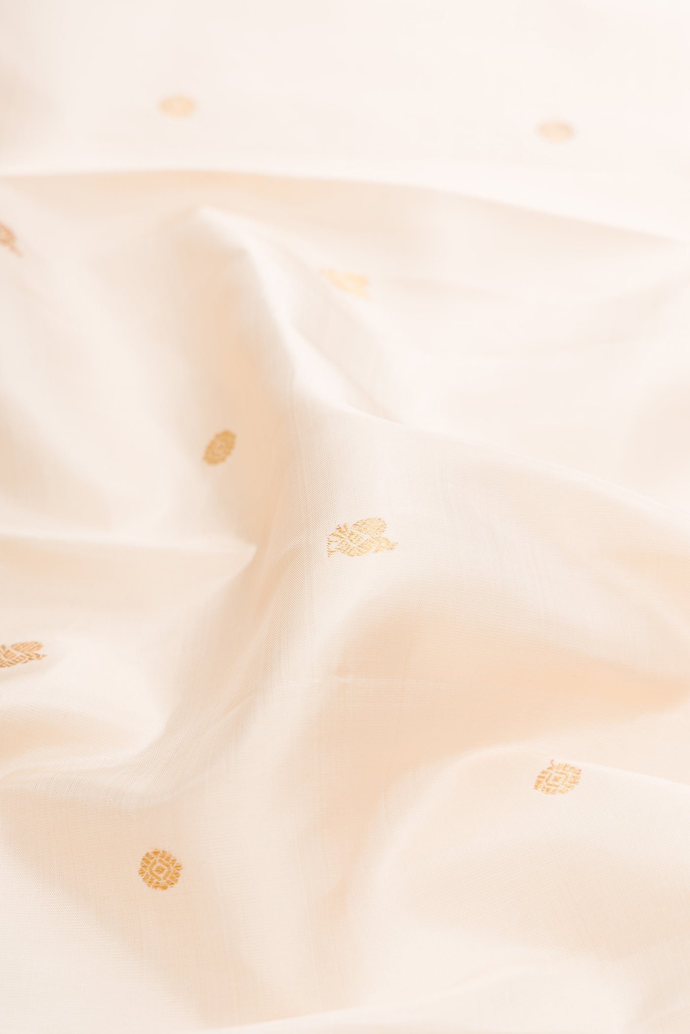 Close up of Pure Silk Pure Zari Beige Dual Tone Kanjivaram Saree with Zari Butta on the body and Zari Border.  displaying folds