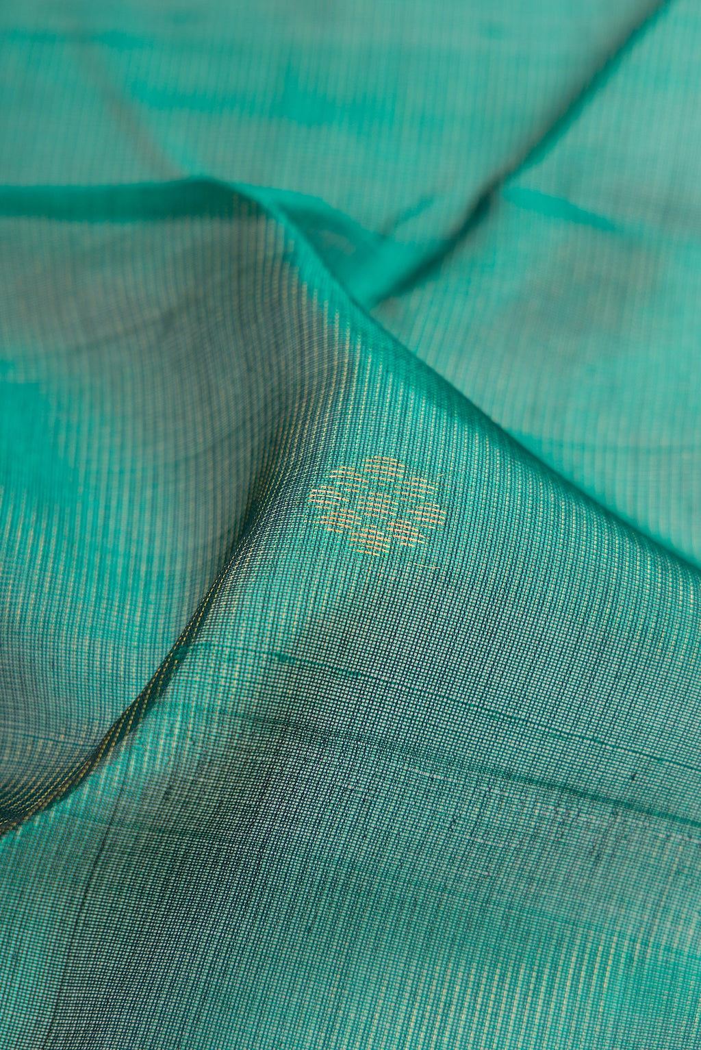 Close up of Bottle Green Silk Cotton Saree with Zari Butta on the body and Zari Border.  displaying folds