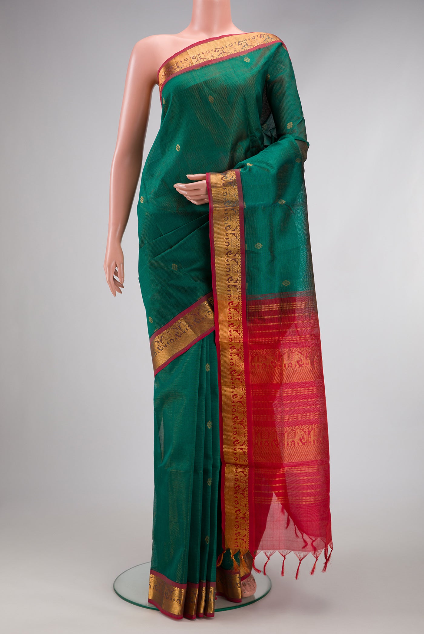 Bottle Green Silk Cotton Saree with Zari Butta on the body and Zari Border.  displayed on a mannequin