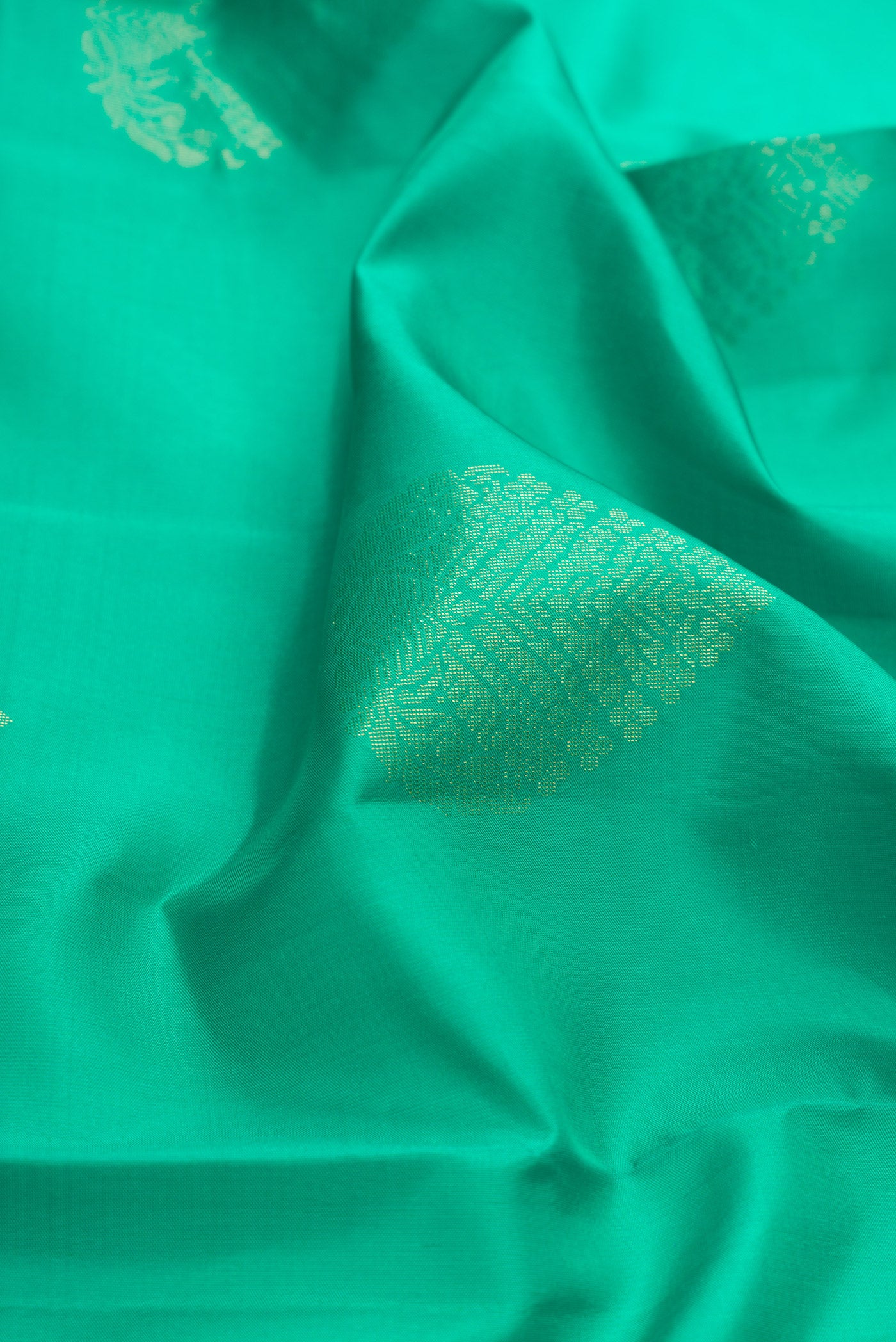 Close up of Green Dual Tone Soft Silk Saree with Zari Butta on the body and Zari Border.  displaying folds