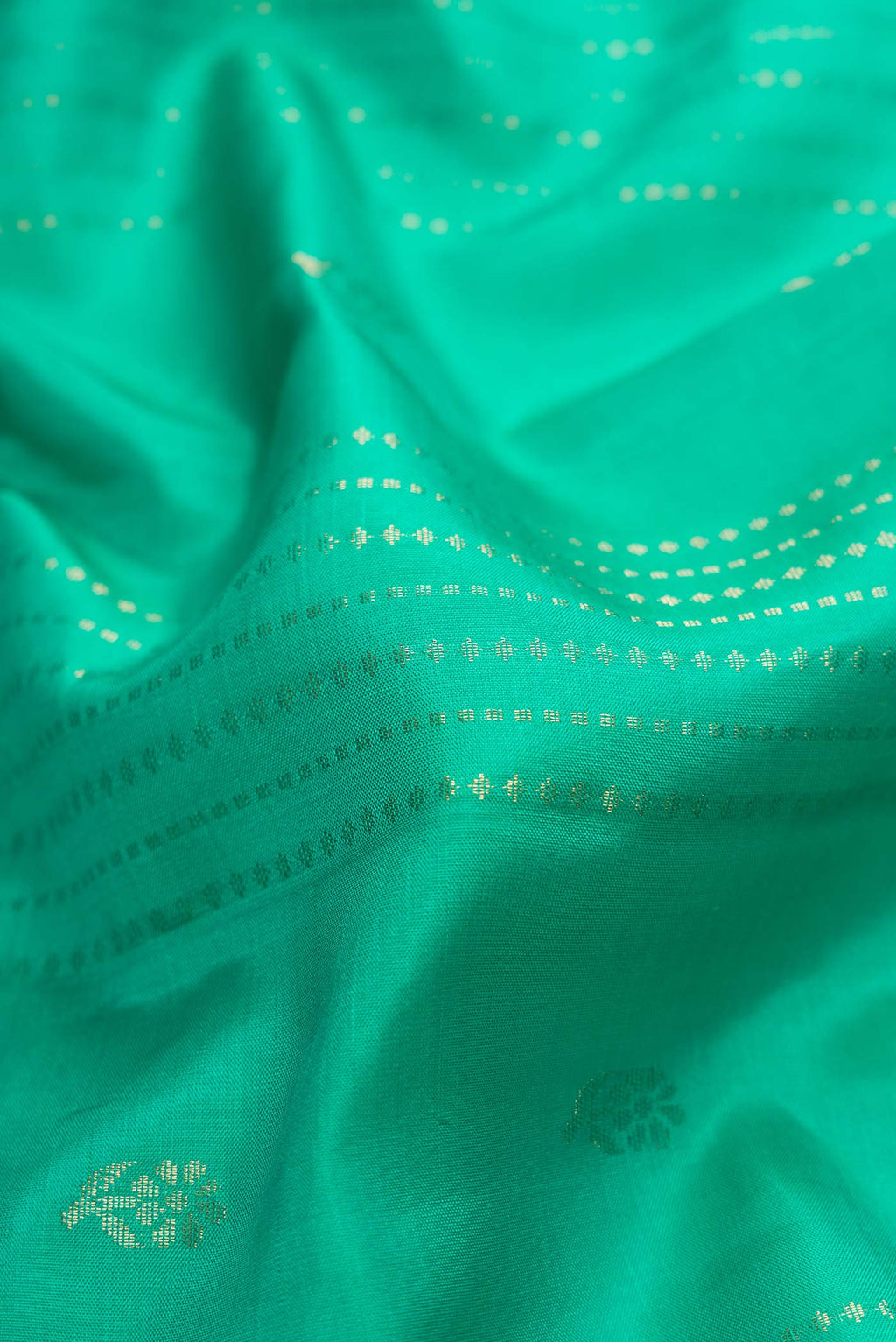 Close up of Green Dual Tone Soft Silk Saree with Zari Butta on the body and Zari Border.  displaying folds