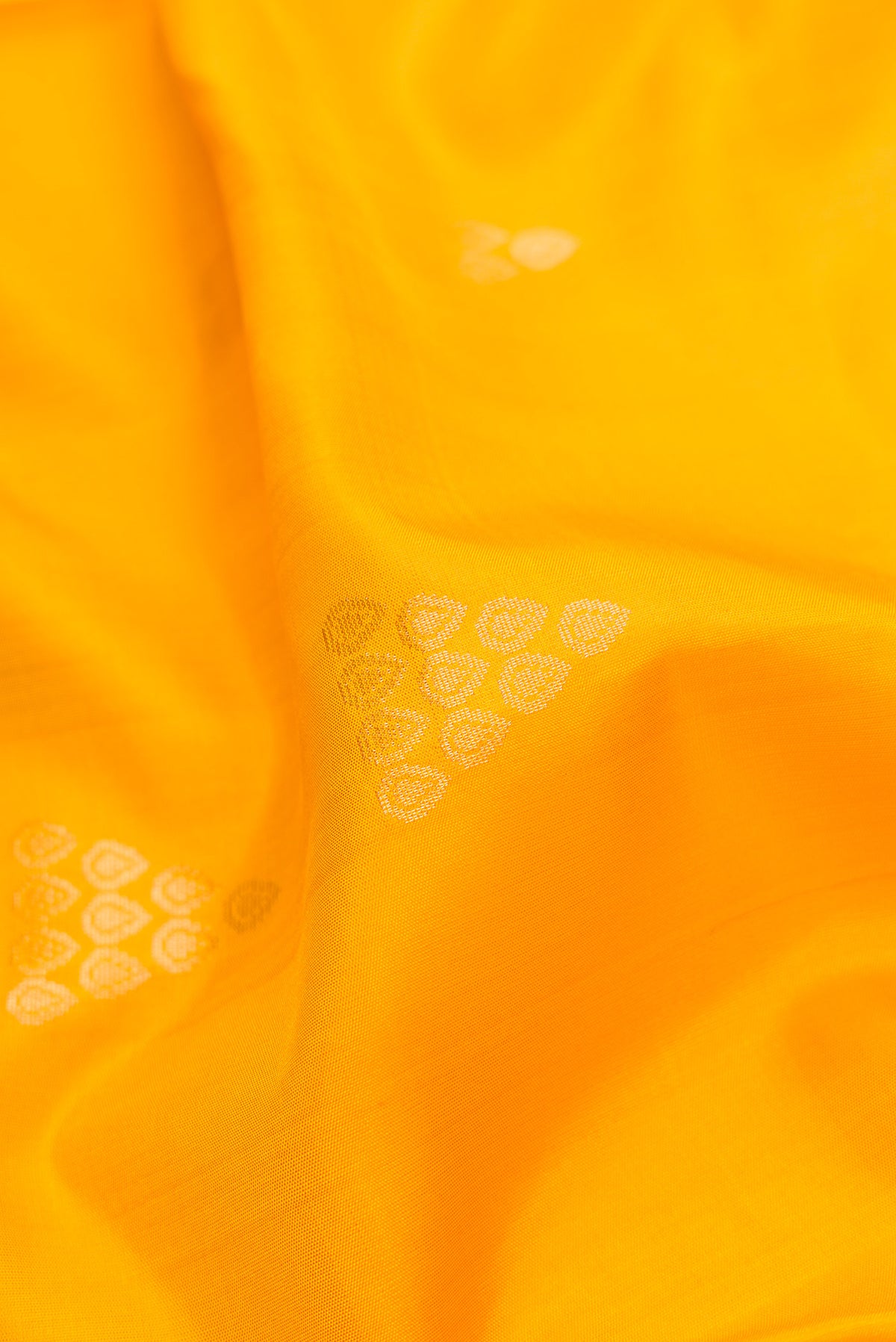 Close up of Yellow Dual Tone Soft Silk Saree with Zari Butta on the body and Zari Border.  displaying folds