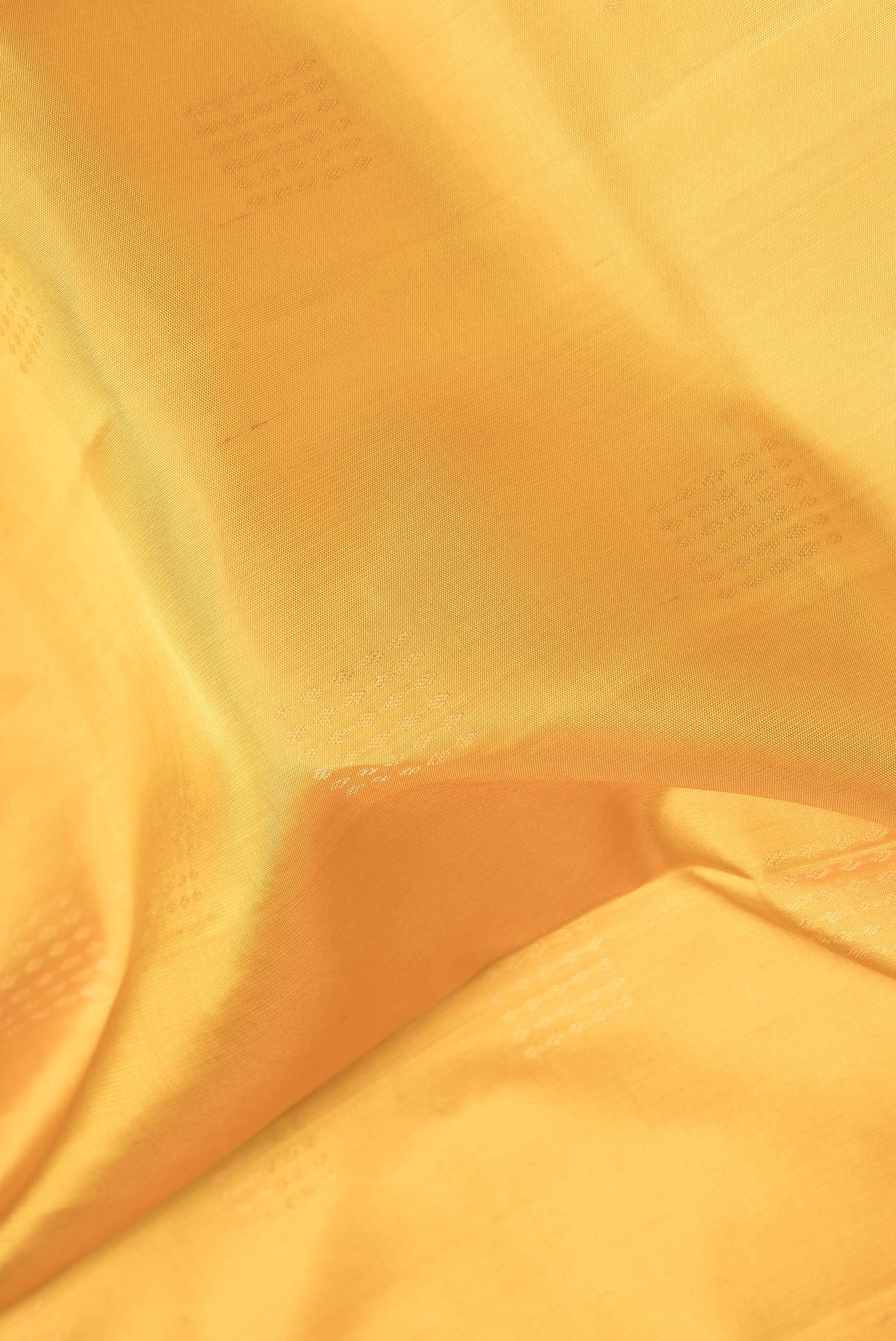 Close up of Yellow Dual Tone Soft Silk Saree with Zari Butta on the body and Zari Border.  displaying folds
