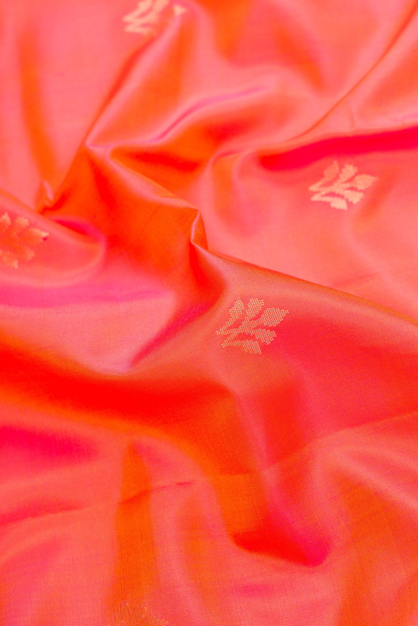 Close up of Orange Dual Tone Soft Silk Saree with Zari Butta on the body and Zari Border.  displaying folds