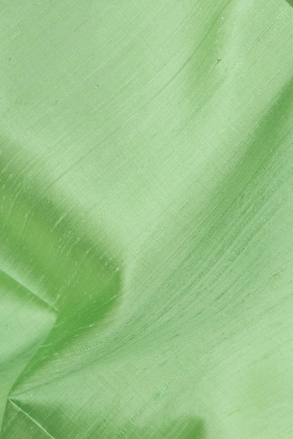 Close up of Pure Silk Pista Green Raw Saree with Plain Body and Zari Border.  displaying folds