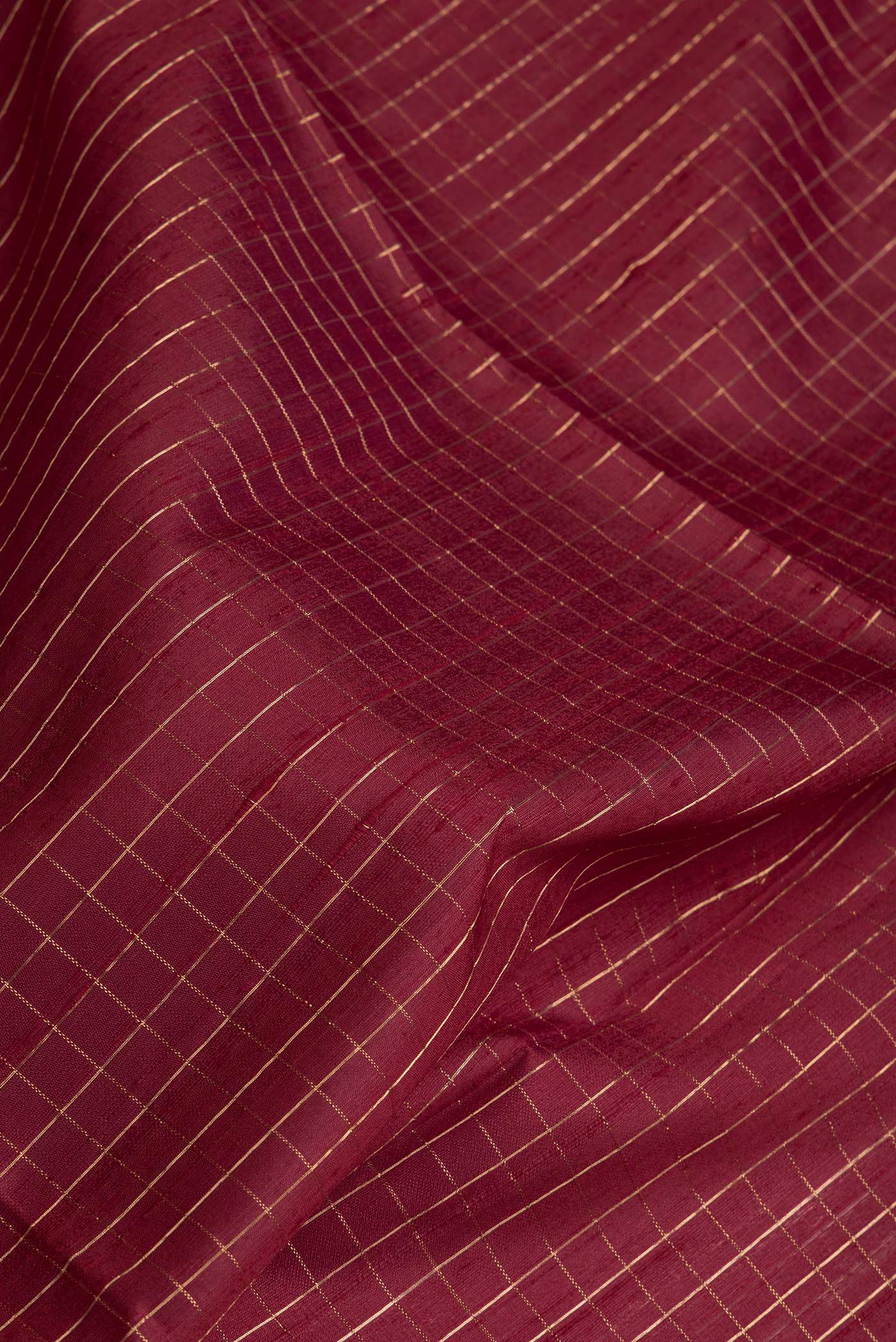 Close up of Maroon Dual Tone Raw Silk Saree with Checked design on the body and Thin Zari Line.  displaying folds
