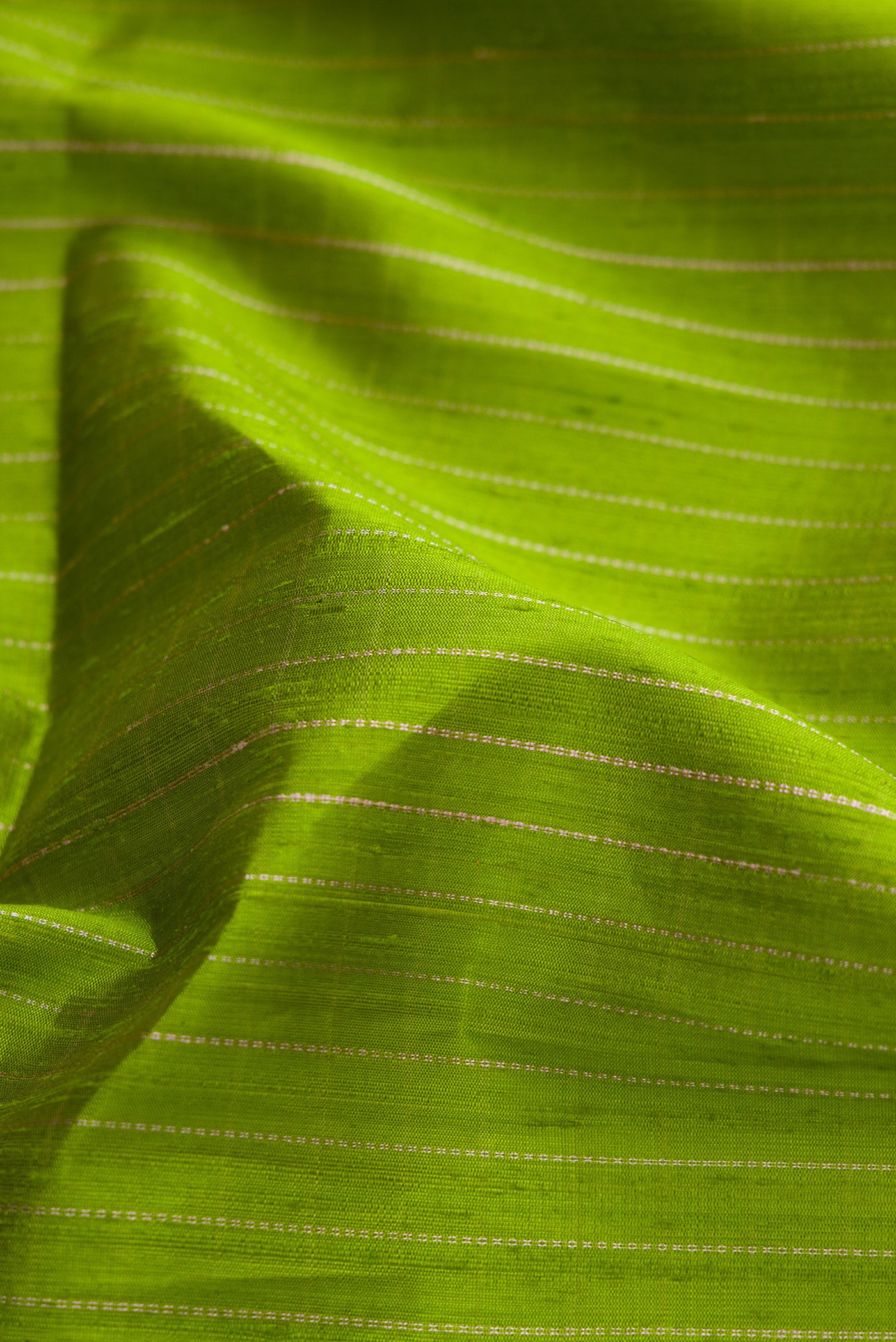 Close up of Parrot Green Dual Tone Raw Silk Saree with Zari Butta on the body and Zari Border.  displaying folds