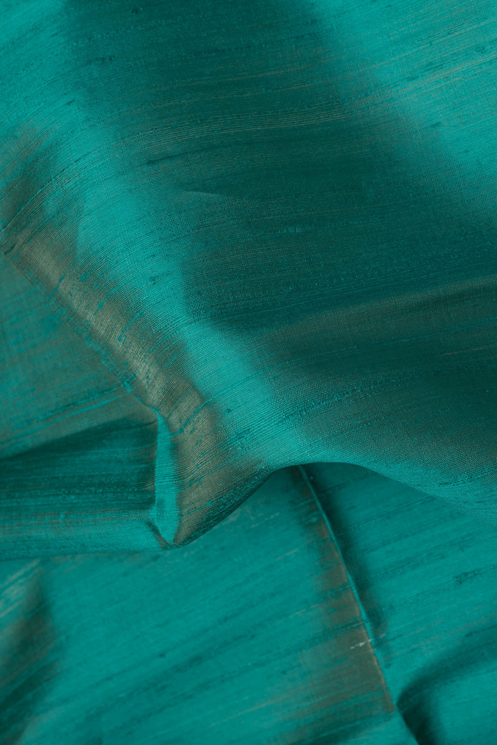 Close up of Peacock Blue Dual Tone Raw Silk Saree with Plain Body and Thin Zari Line.  displaying folds