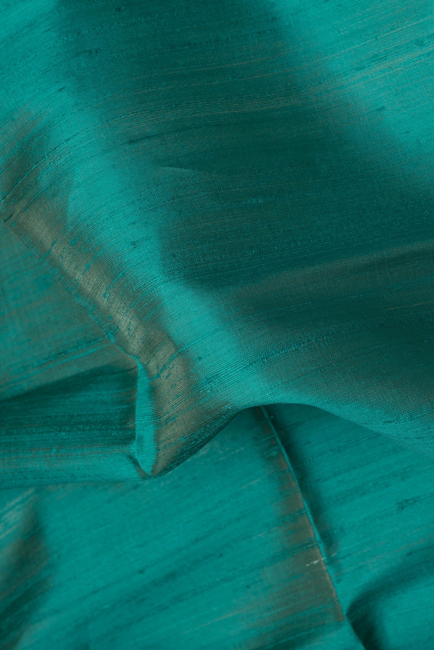 Close up of Peacock Blue Dual Tone Raw Silk Saree with Plain Body and Thin Zari Line.  displaying folds