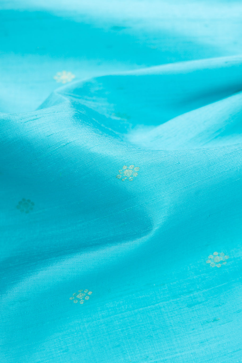 Close up of Sky Blue Dual Tone Raw Silk Saree with Zari Butta on the body and Thin Zari Line.  displaying folds